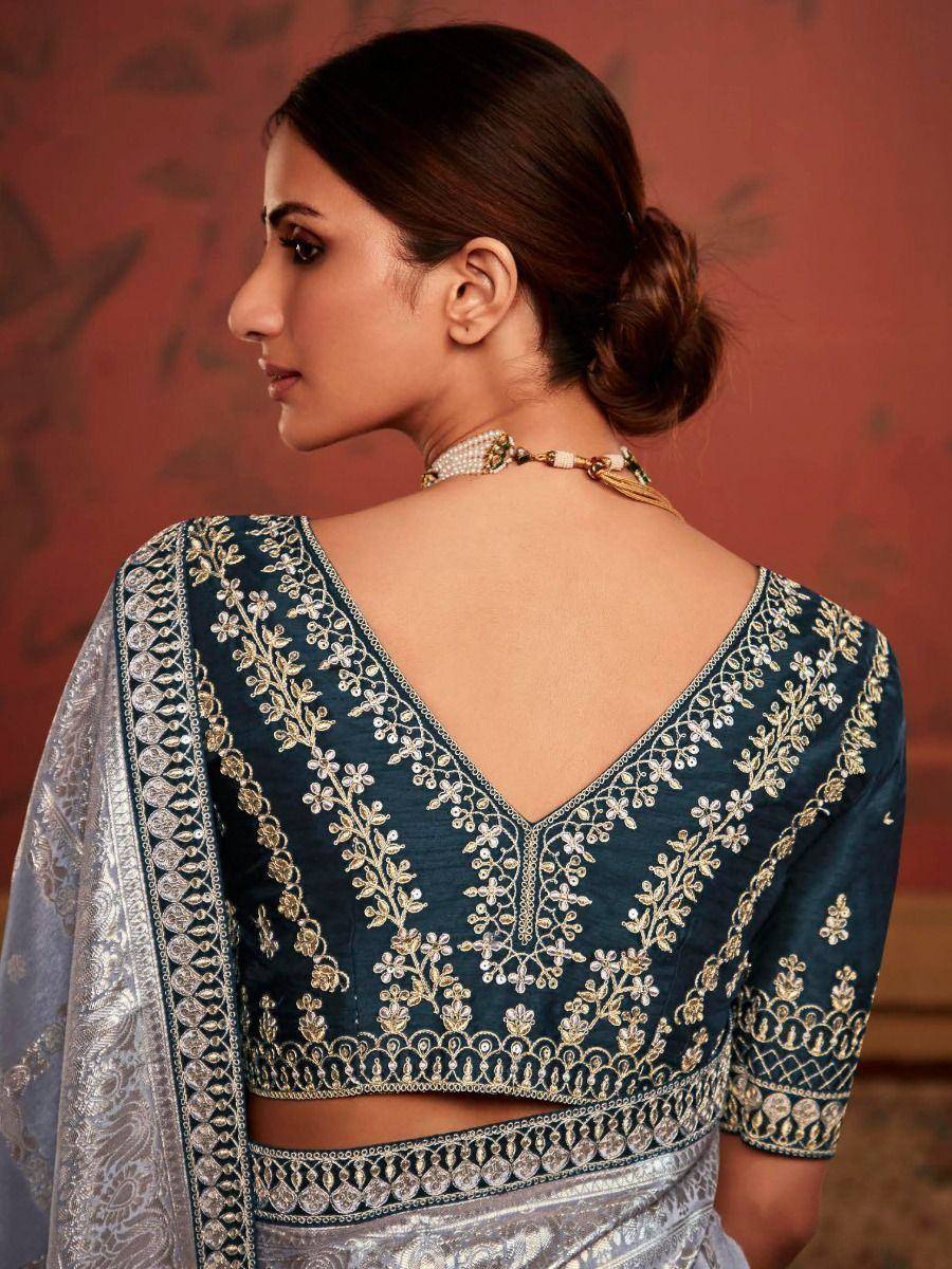 Elegant teal designer blouse with gold floral embroidery, paired with silver saree, perfect for Indian ethnic wear