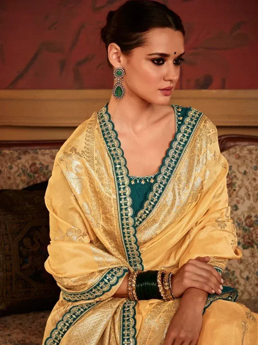 Elegant gold and teal ethnic saree with intricate embroidery and matching jewelry