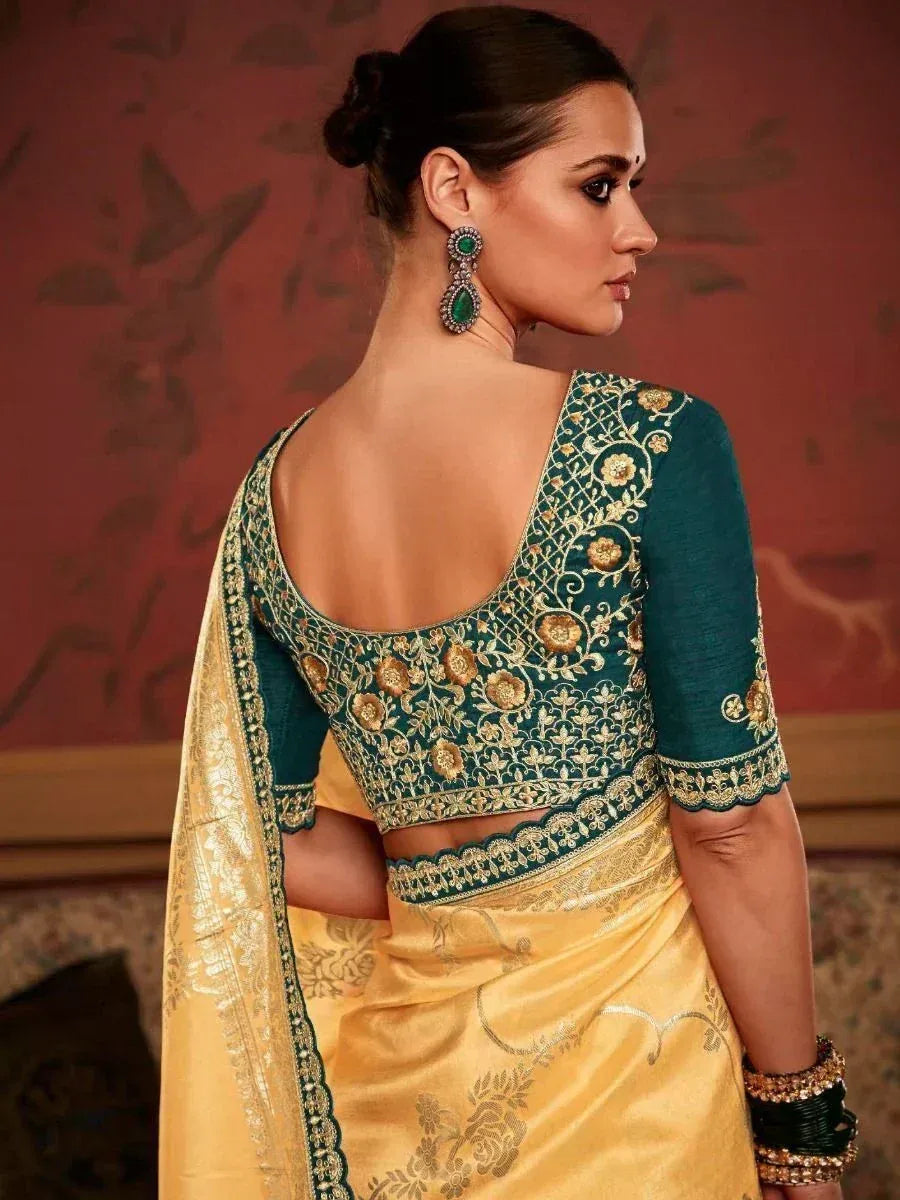 Teal embroidered blouse with gold floral work paired with yellow saree, showcasing elegant Indian ethnic wear.
