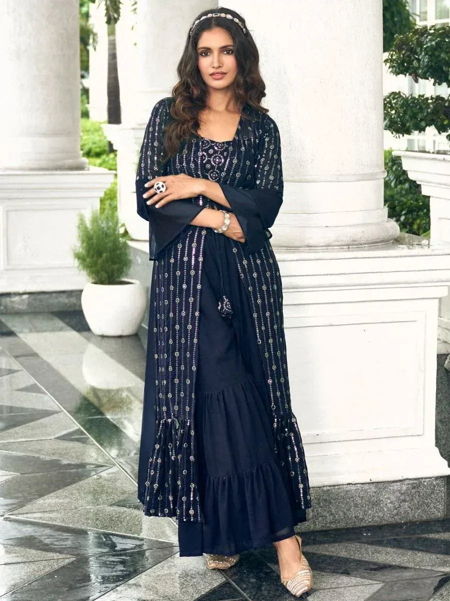 Woman in navy blue ethnic gown with silver embellishments, posing outdoors by white pillars