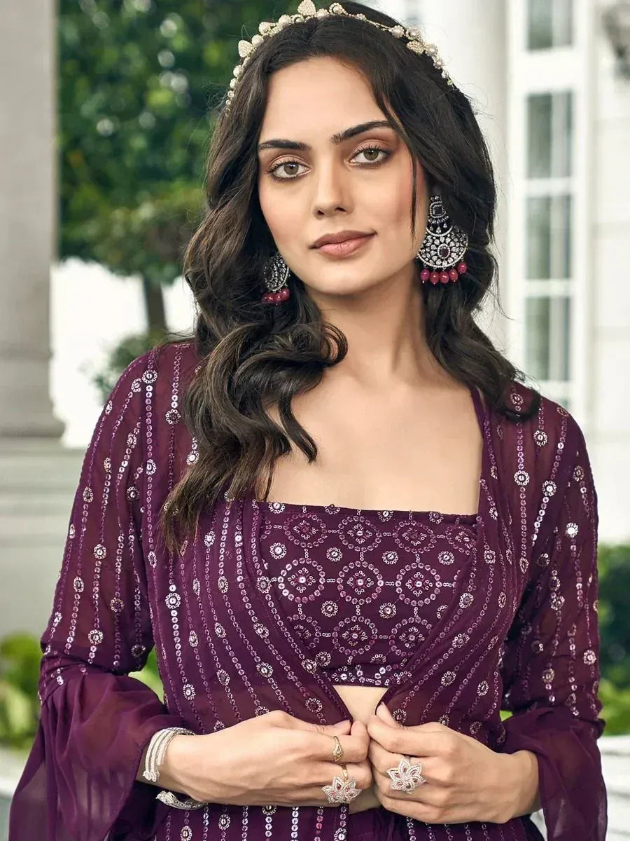 Woman in embellished purple lehenga choli with sequin design, wearing ethnic jewelry