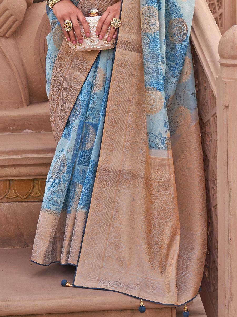 Blue and gold designer saree with intricate patterns, paired with ornate clutch and jewelry, perfect for ethnic occasions.