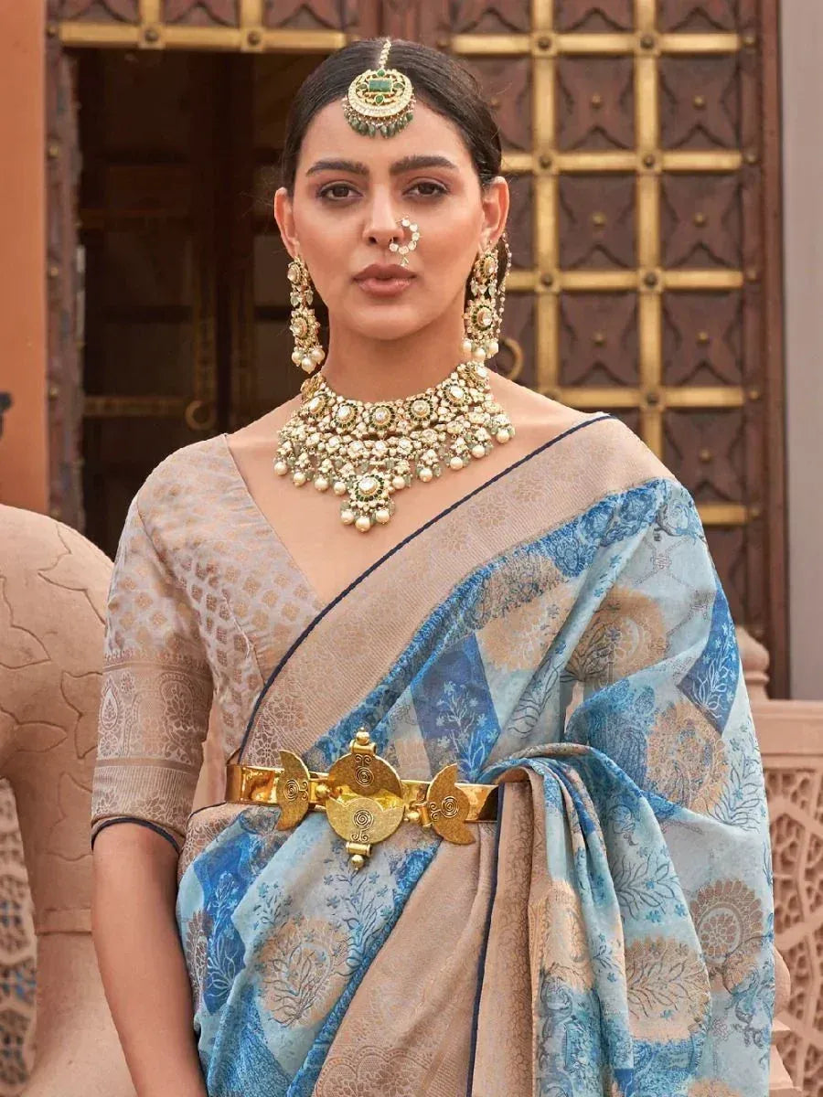 Woman in blue and beige printed saree with gold jewelry and traditional Indian headpiece