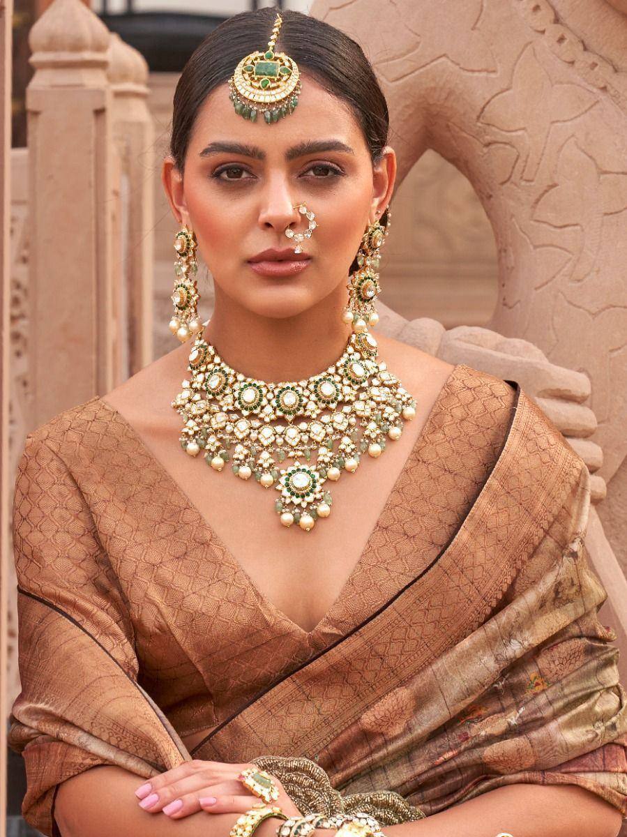 Woman in ethnic saree with green and gold jewelry, traditional Indian attire