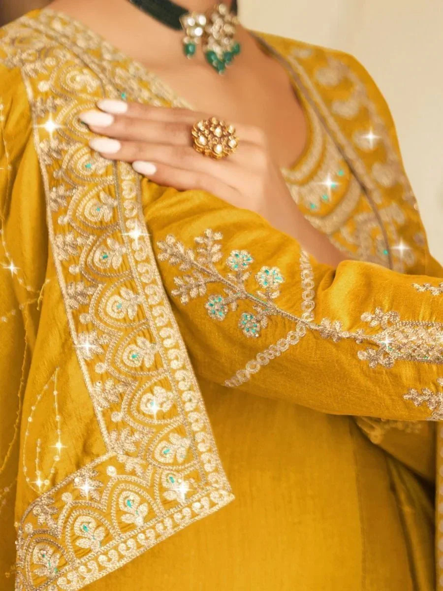 Close-up of mustard yellow embroidered ethnic suit with intricate silver and turquoise zari work.