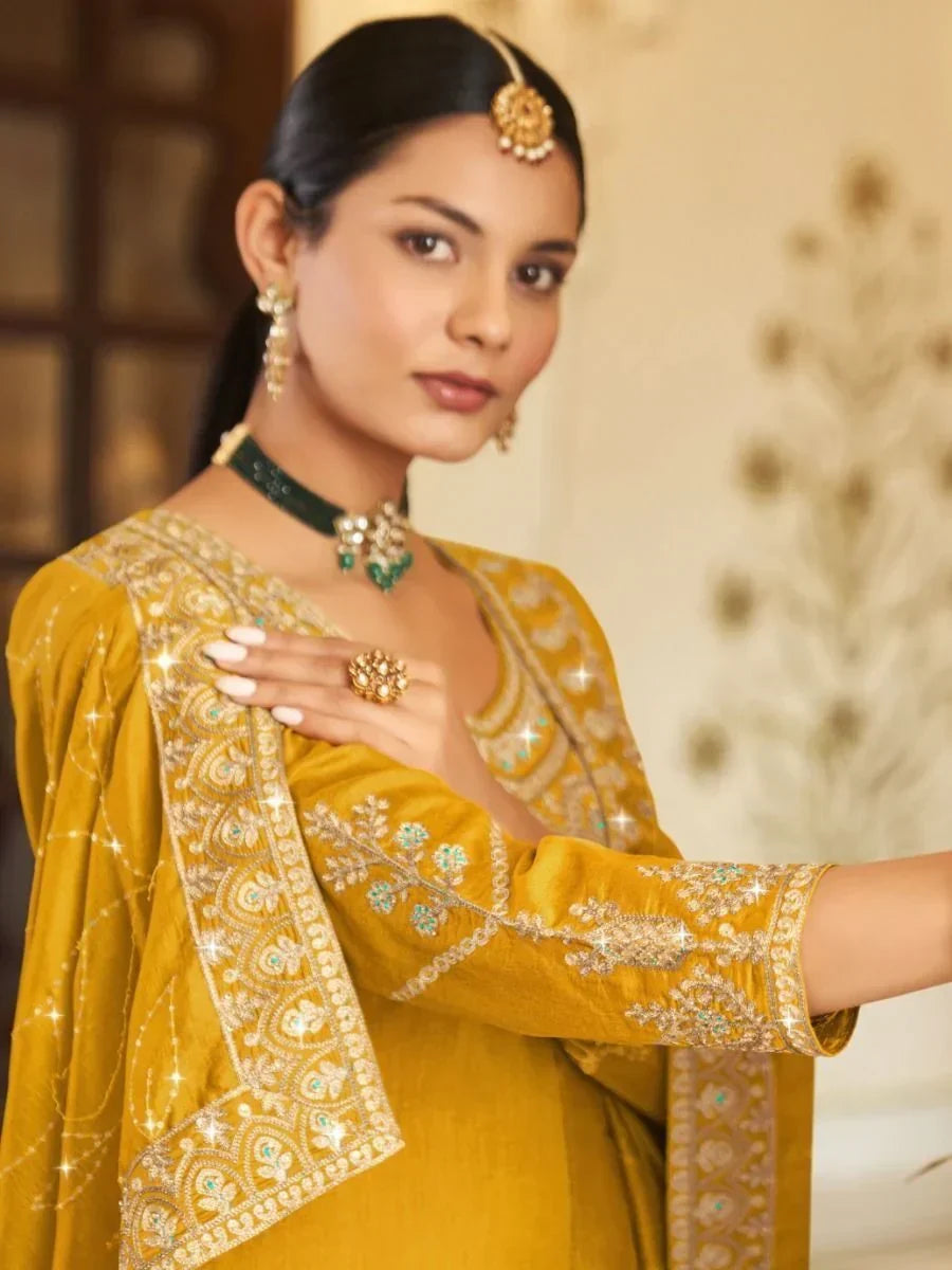 Woman in mustard yellow embroidered salwar kameez with dupatta and traditional jewelry