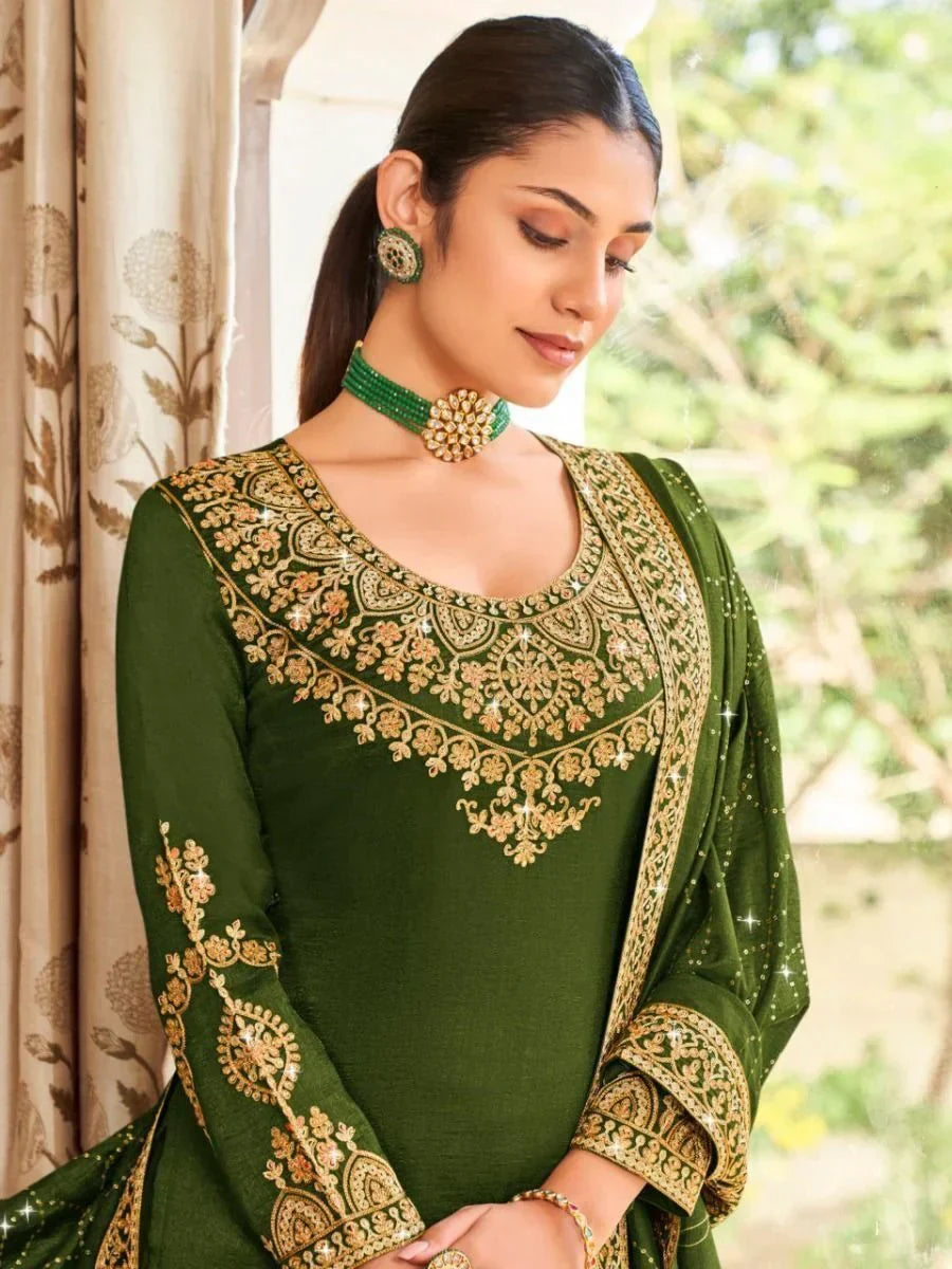Woman in green embroidered Indian salwar kameez with dupatta, wearing ethnic jewelry.