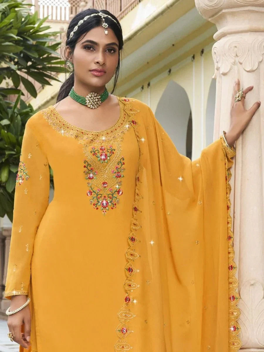 Woman in mustard yellow embroidered salwar kameez with dupatta and traditional jewelry