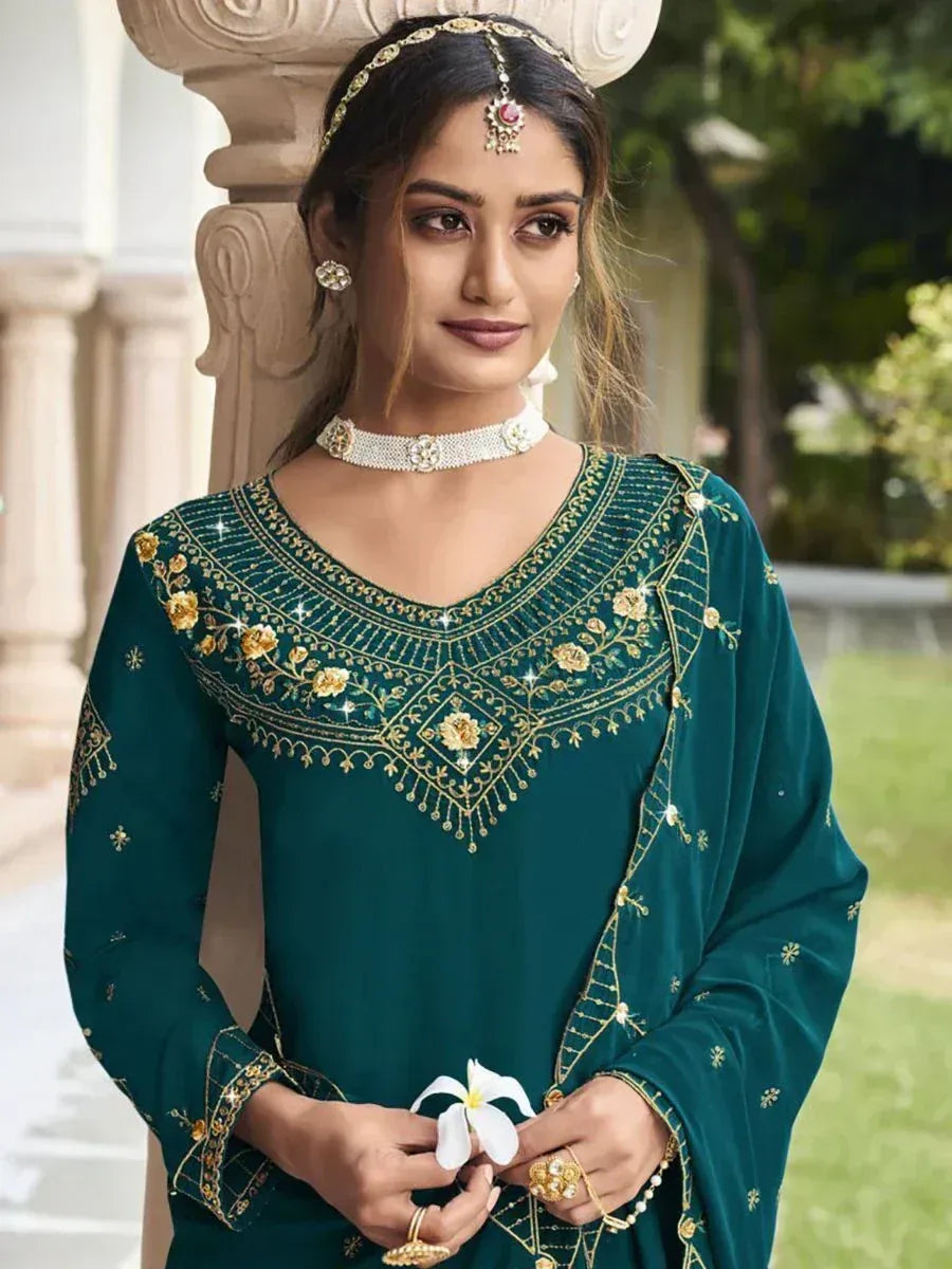 Woman in green embroidered salwar kameez with gold jewelry, outdoor ethnic fashion