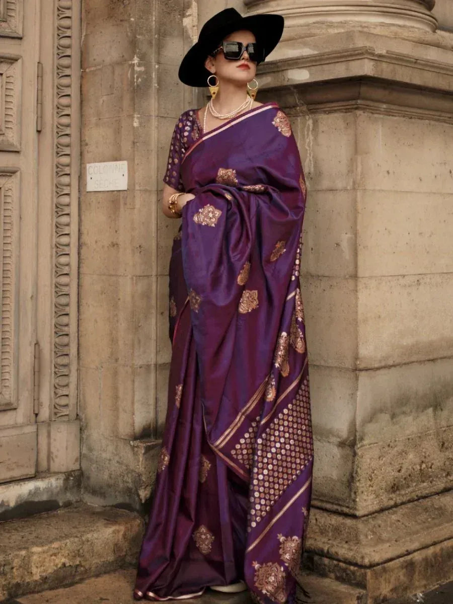 Purple designer saree with gold embroidery, paired with black hat and statement jewelry for ethnic fashion