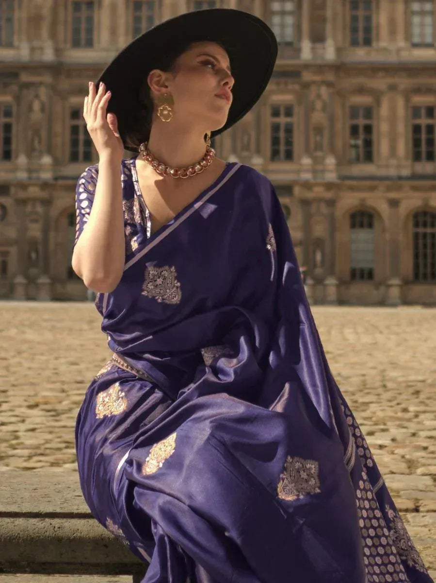 Elegant purple saree with gold embroidery, styled with wide-brim hat and statement jewelry for ethnic fashion.