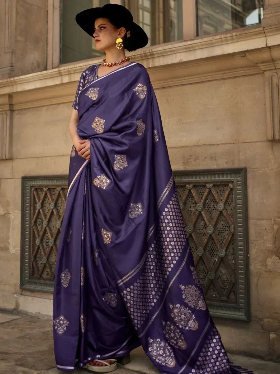 Elegant purple designer saree with gold embroidery, styled with black hat and statement jewelry for ethnic wear.