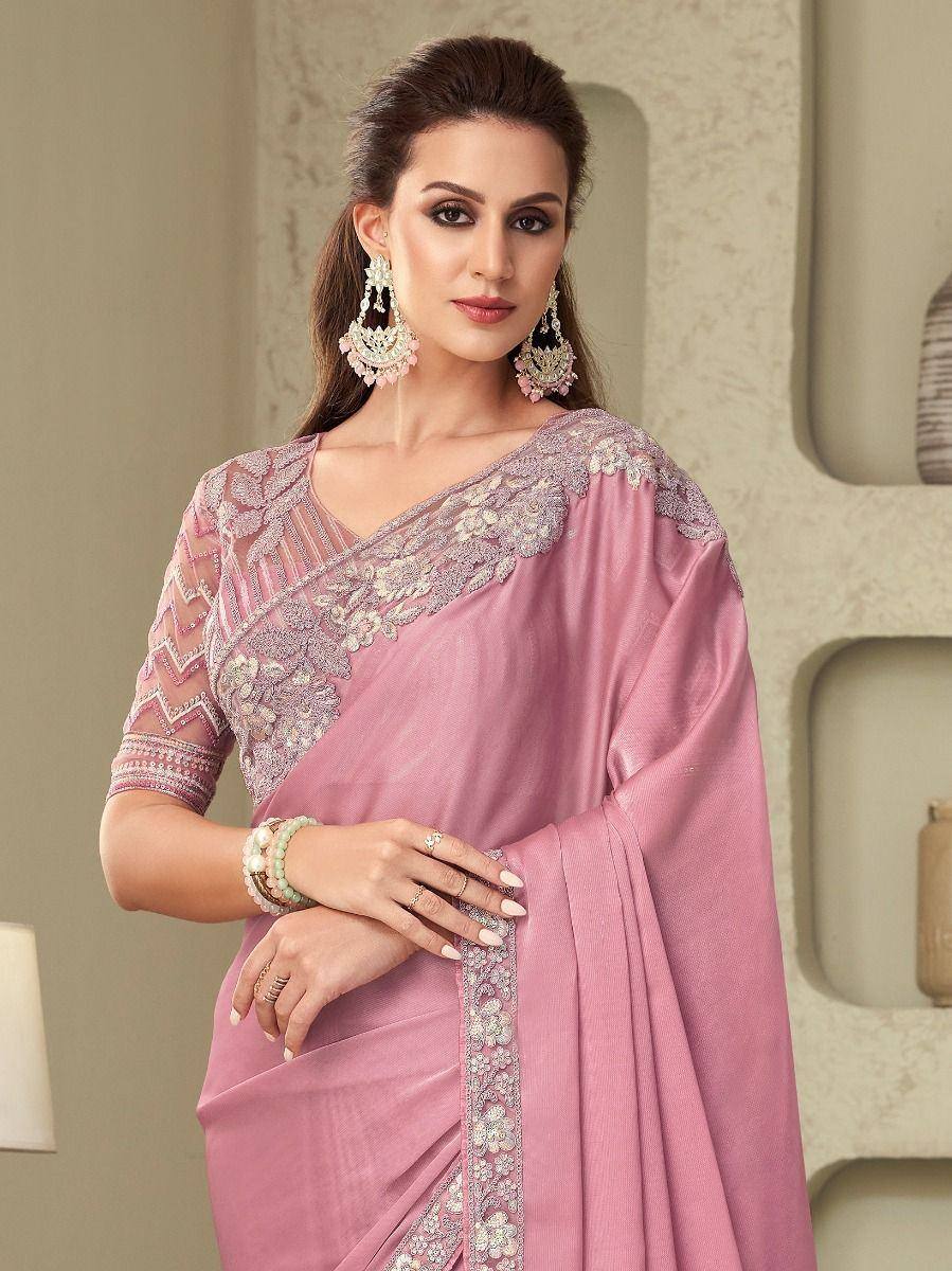 Pink embroidered saree with floral embellishments and sheer sleeves, styled with statement earrings