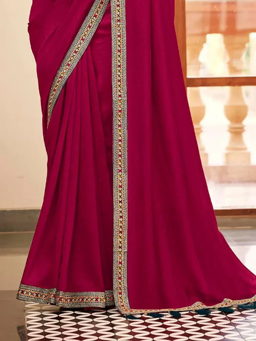 Rich magenta saree with intricate embroidered border and tassels, perfect for ethnic occasions