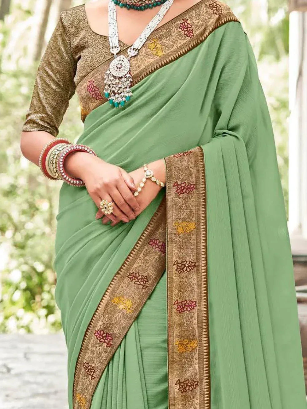 Green saree with gold floral border, paired with embroidered blouse and traditional jewelry