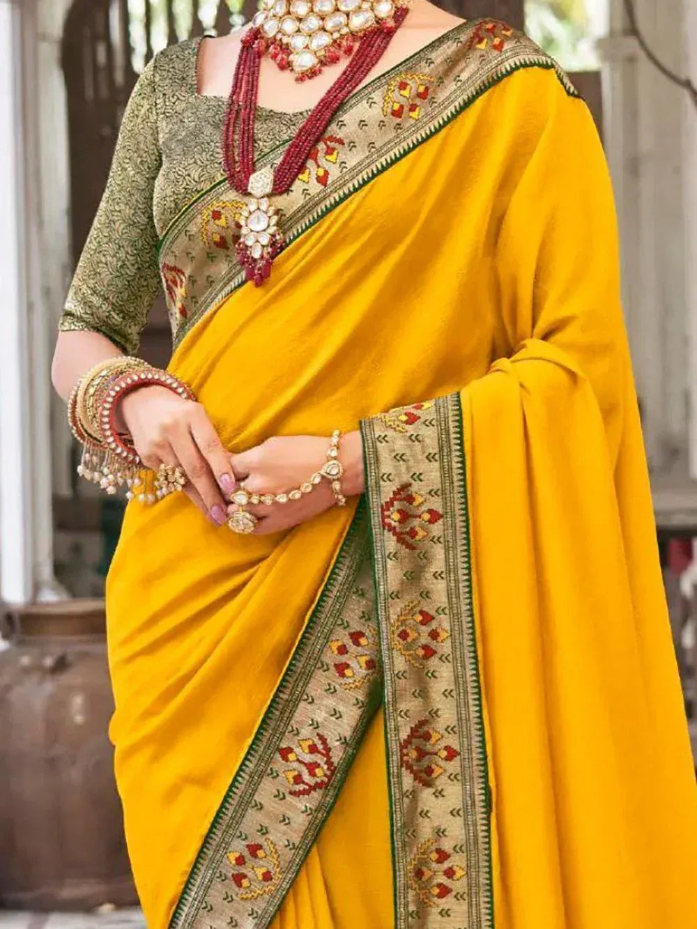 Yellow ethnic saree with embroidered border, paired with green blouse and traditional jewelry
