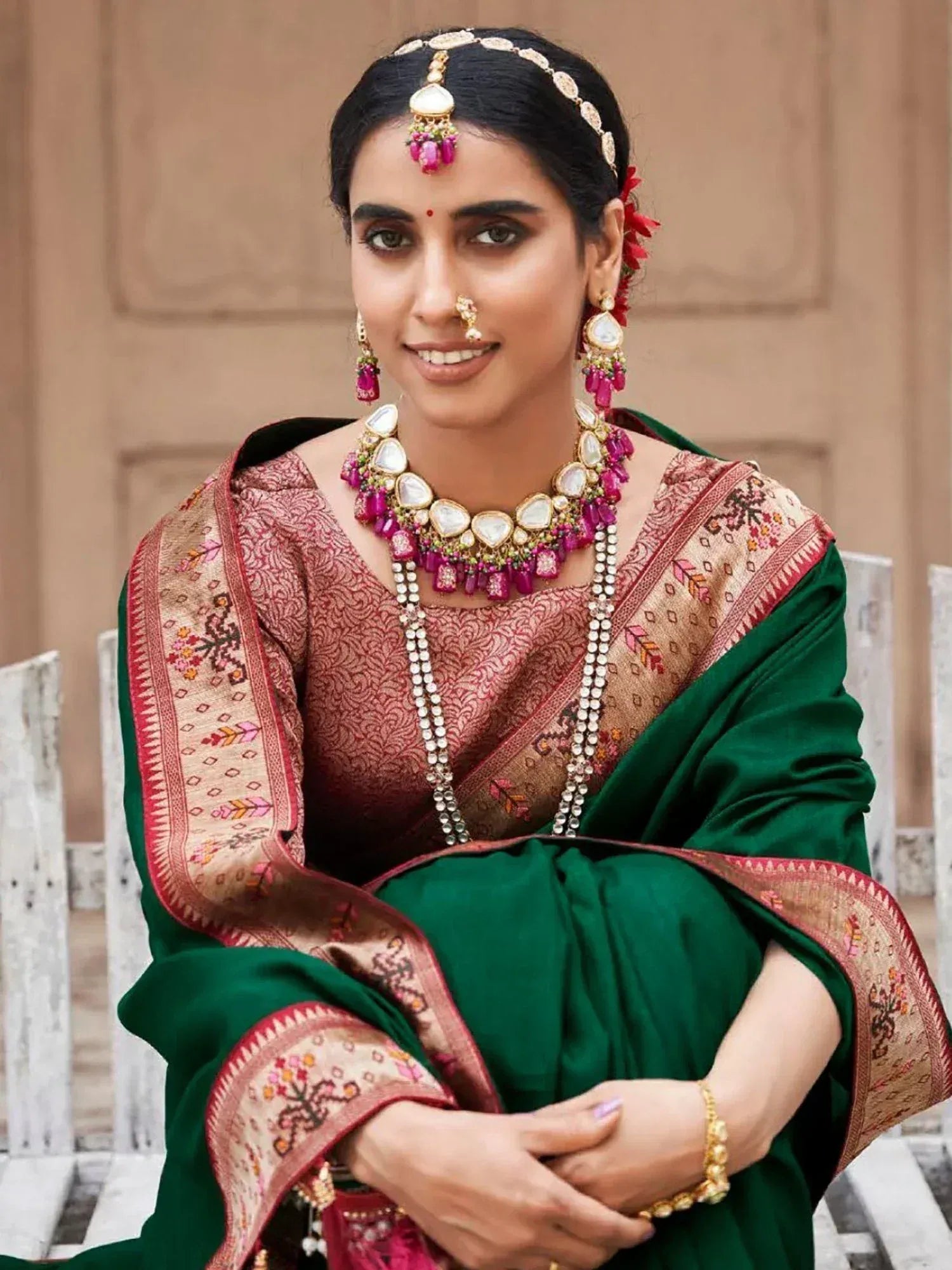 Woman in green and maroon ethnic saree with intricate embroidery and traditional Indian jewelry