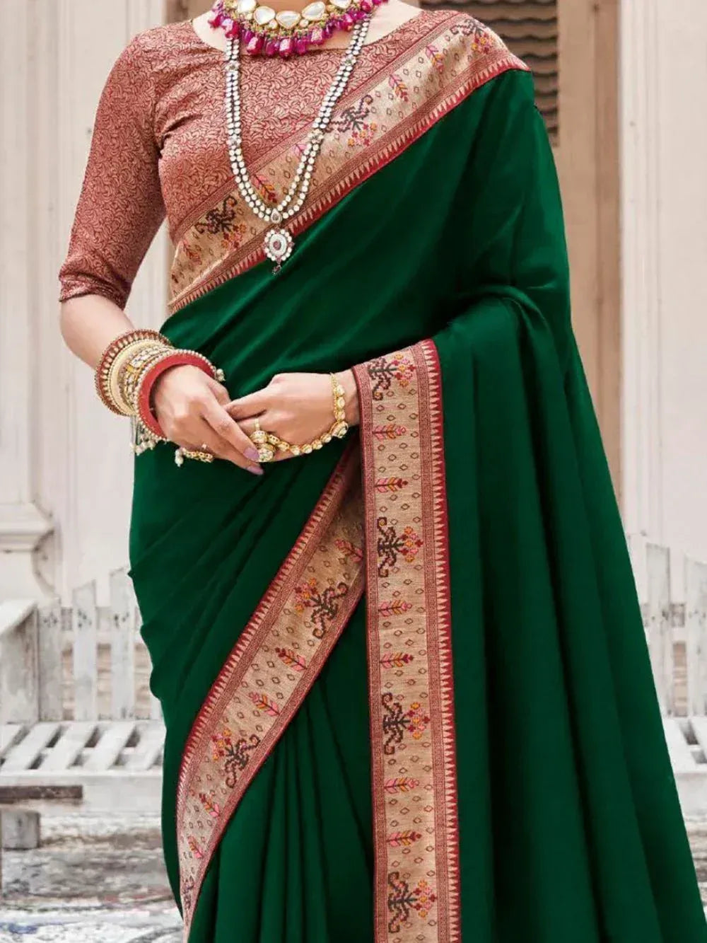 Emerald green saree with embroidered border, paired with patterned blouse and traditional jewelry