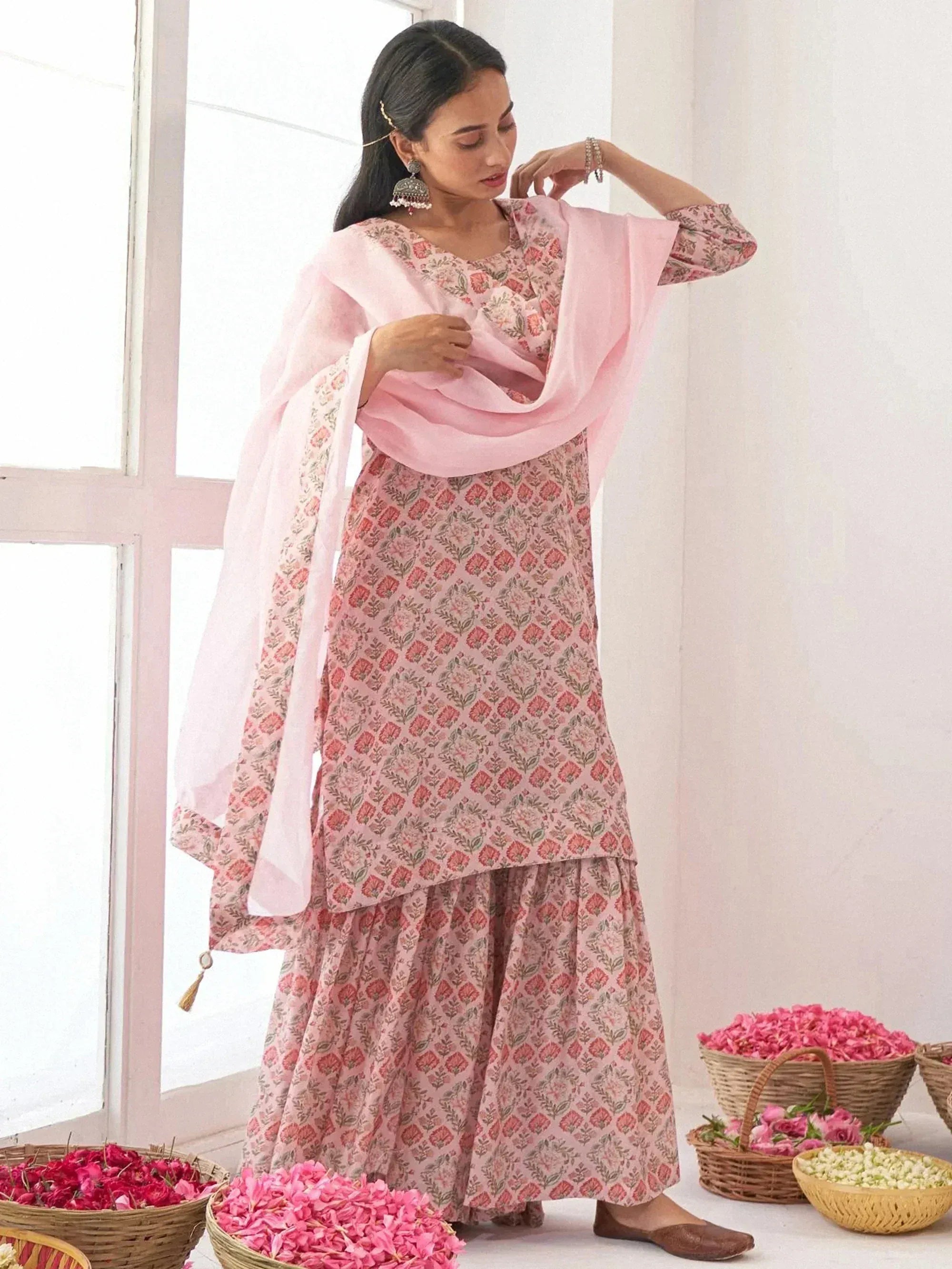 Pink floral printed salwar kameez with matching dupatta, styled with traditional earrings and floral decor