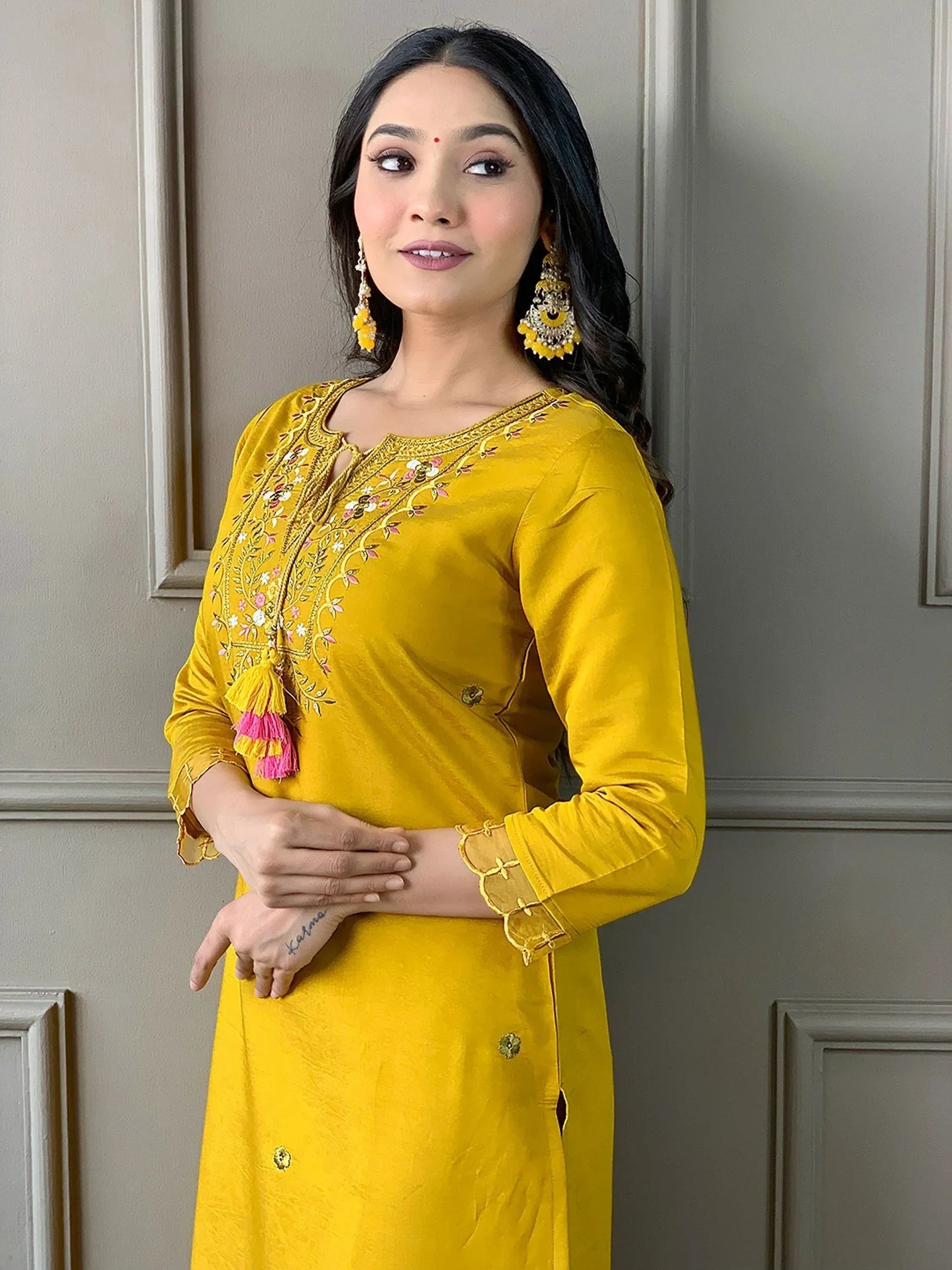 Yellow embroidered ethnic kurti with floral design and tassels, paired with statement earrings