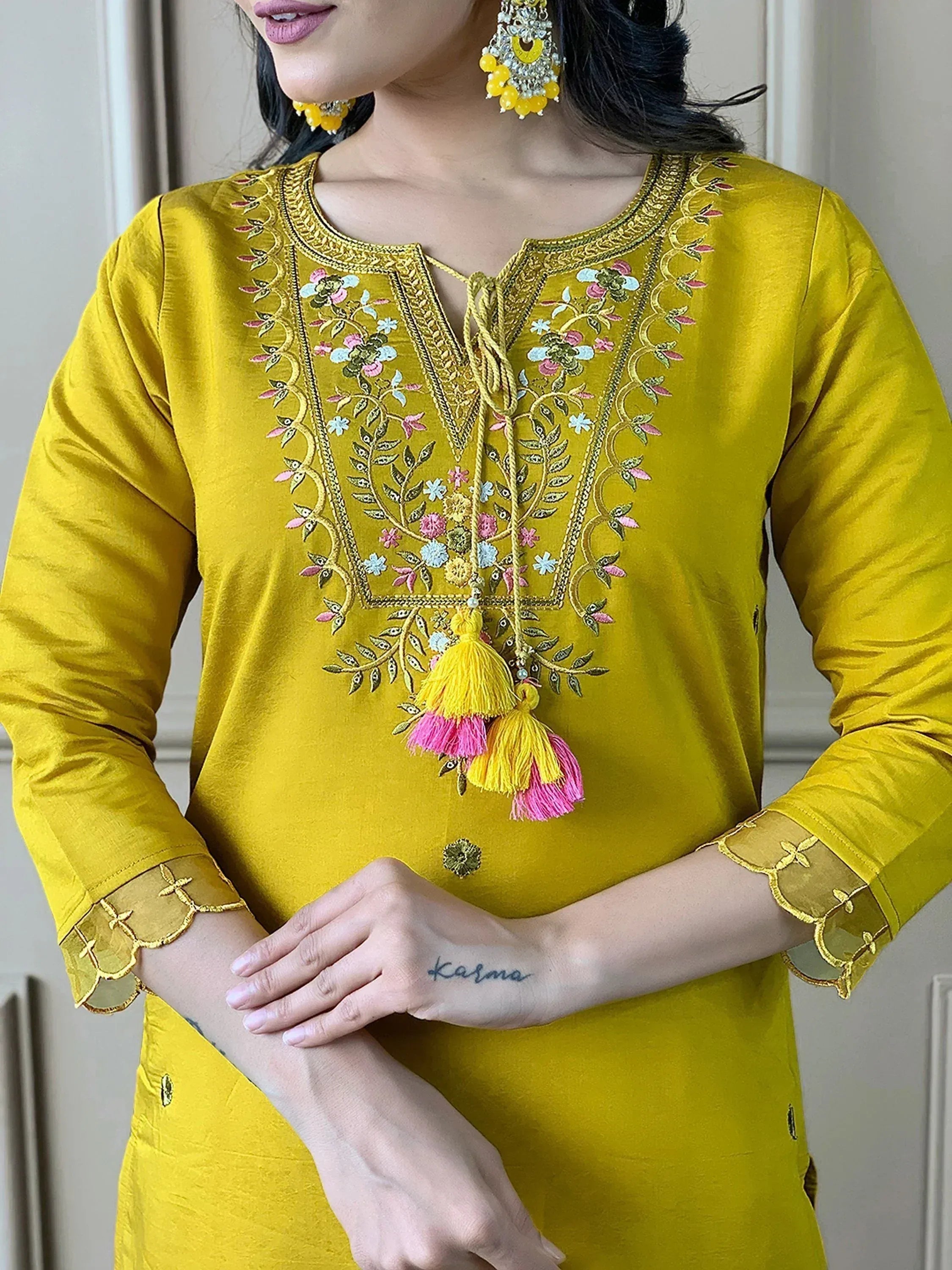 Yellow embroidered ethnic kurti with floral design and tassels, paired with matching jhumka earrings