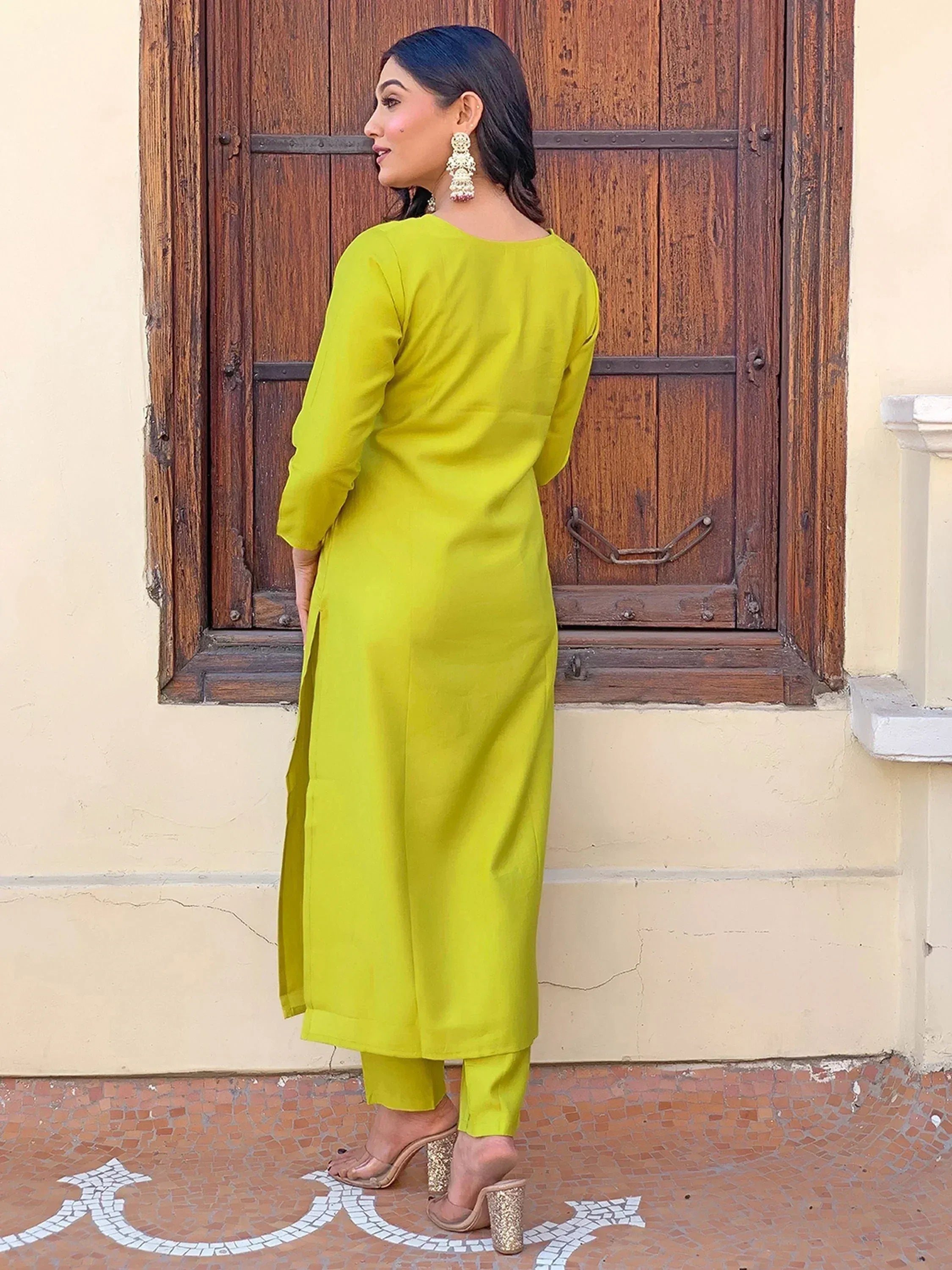 Vibrant lime green kurta set with side slits, paired with matching pants and statement earrings, perfect for ethnic wear.