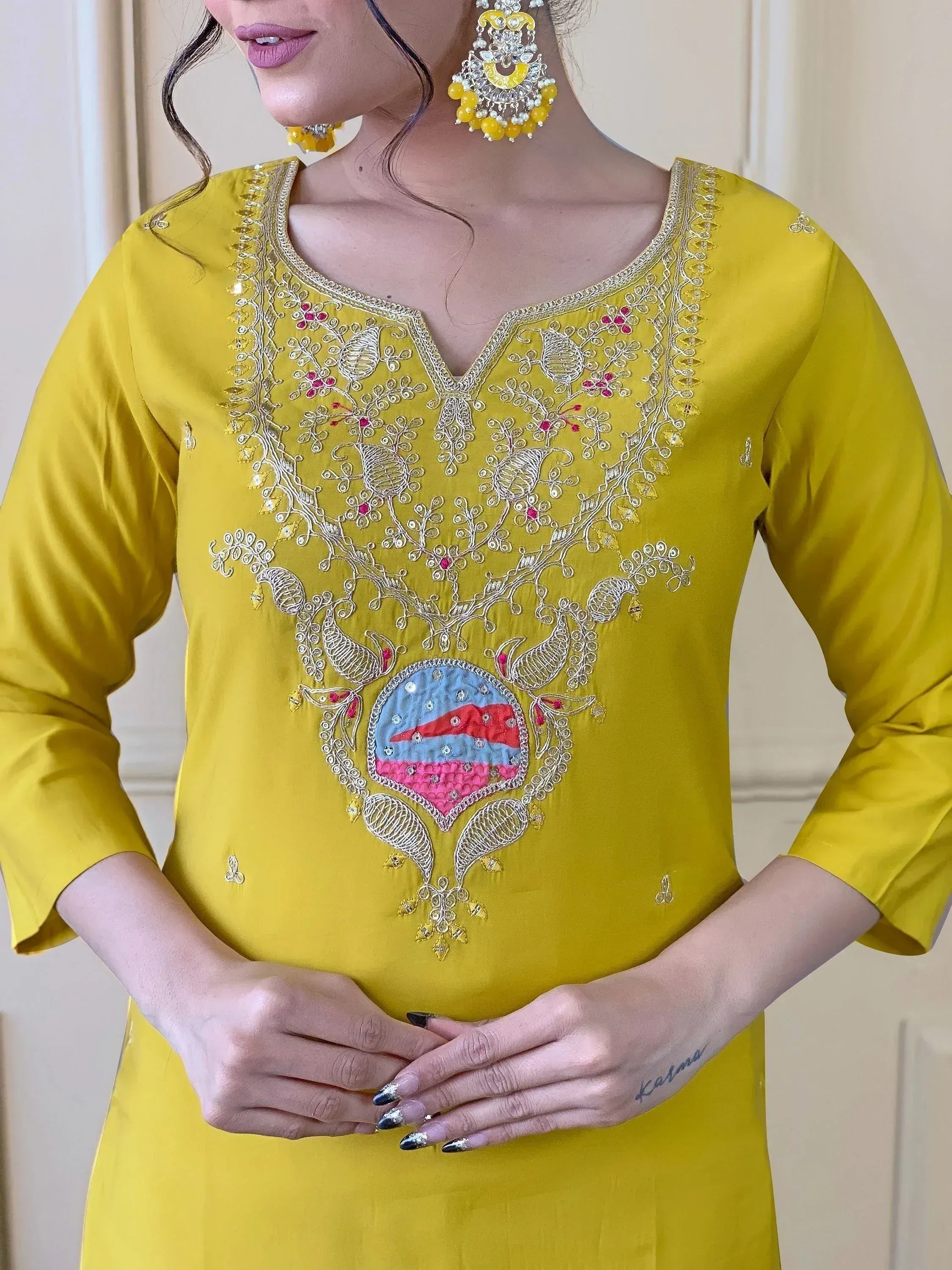 Yellow ethnic kurti with intricate floral embroidery and colorful patchwork, paired with statement earrings