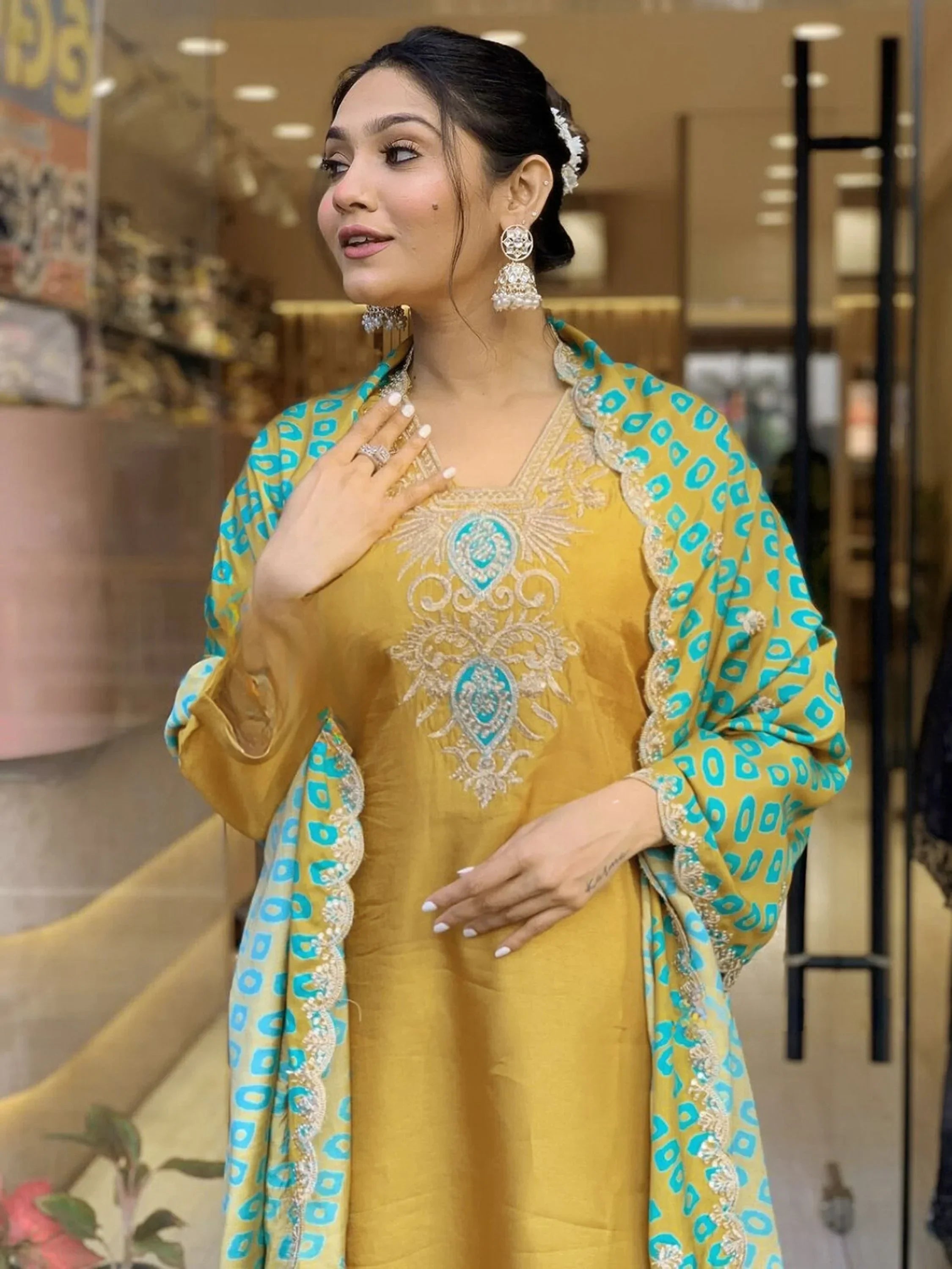 Woman in mustard yellow embroidered salwar kameez with blue dupatta, statement earrings