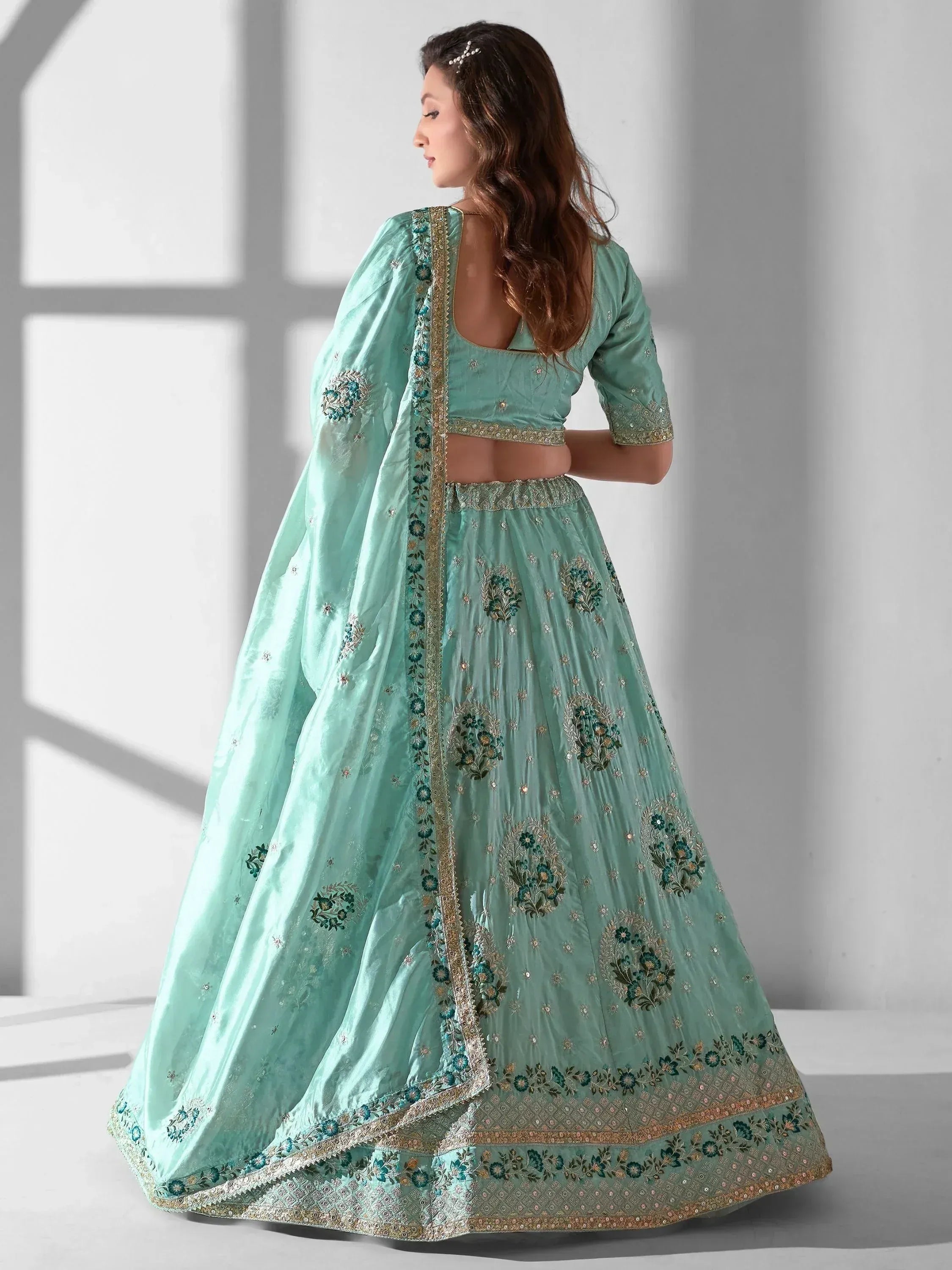 Mint green designer lehenga choli with floral embroidery and gold detailing, perfect for Indian ethnic wear occasions.