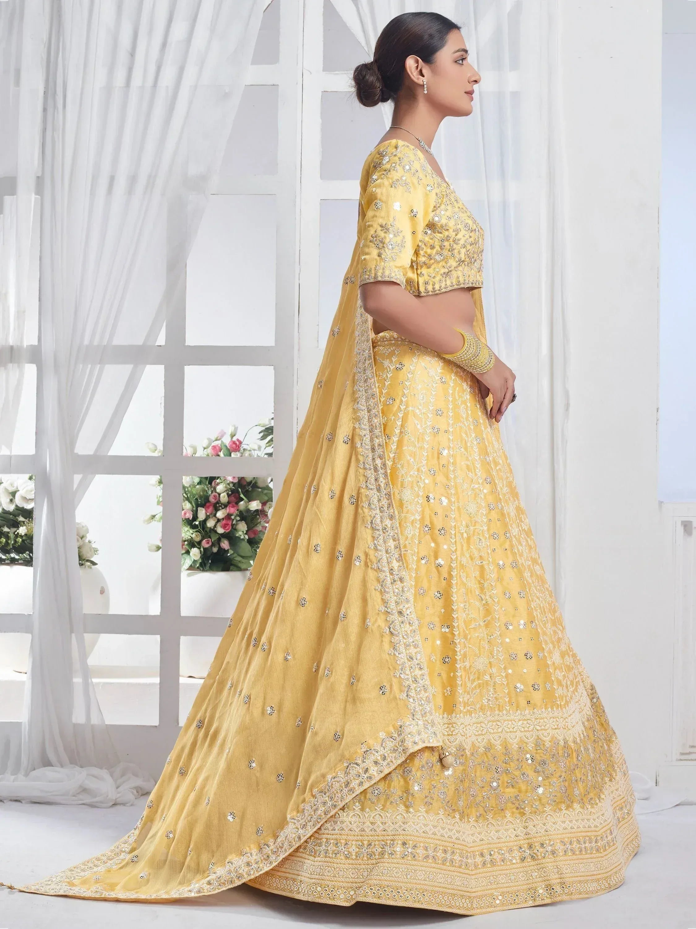 Yellow designer lehenga choli with intricate embroidery and mirror work, perfect for weddings and festive occasions.