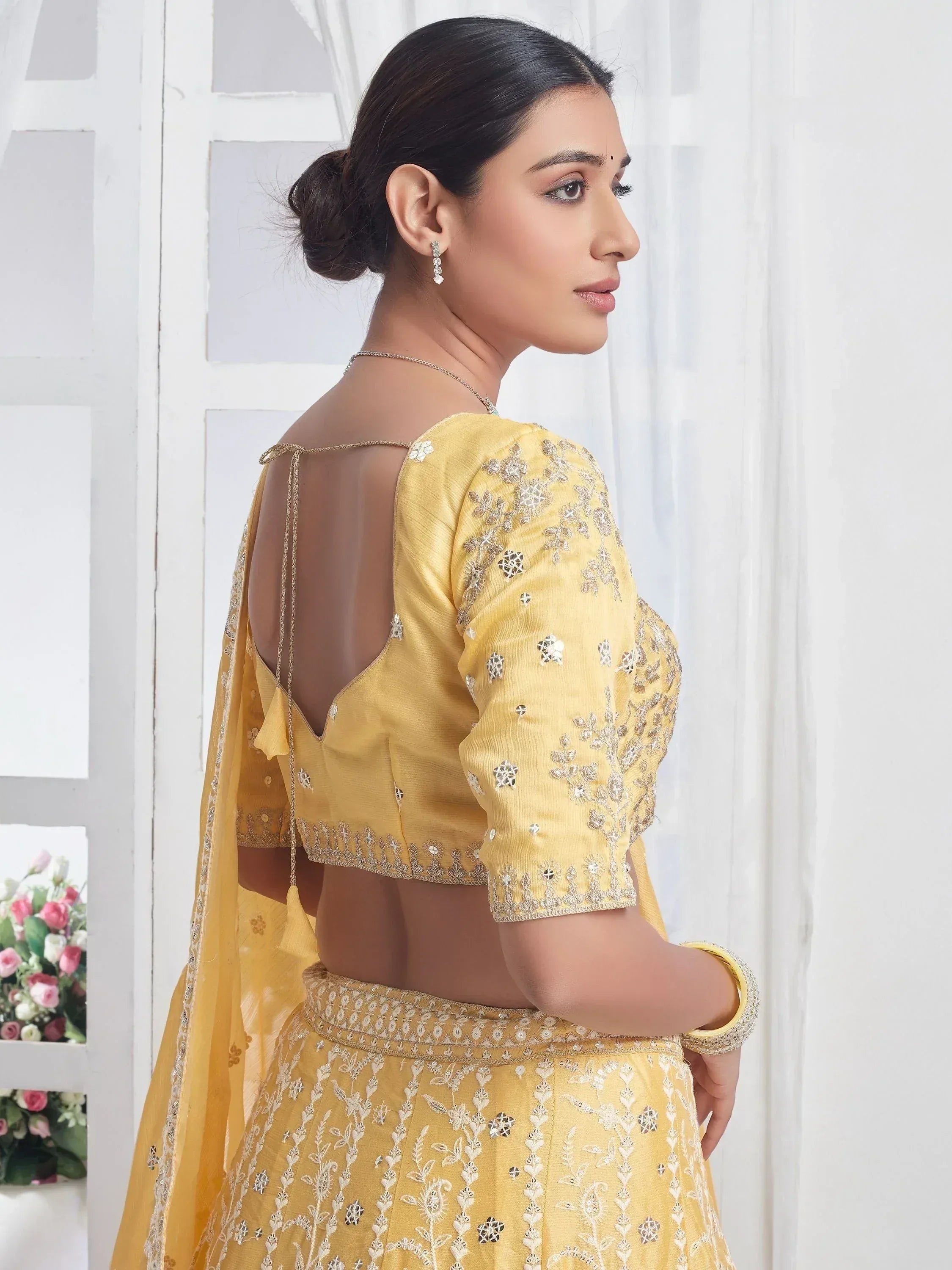 Yellow embroidered lehenga choli with open back design, perfect for Indian ethnic wear occasions