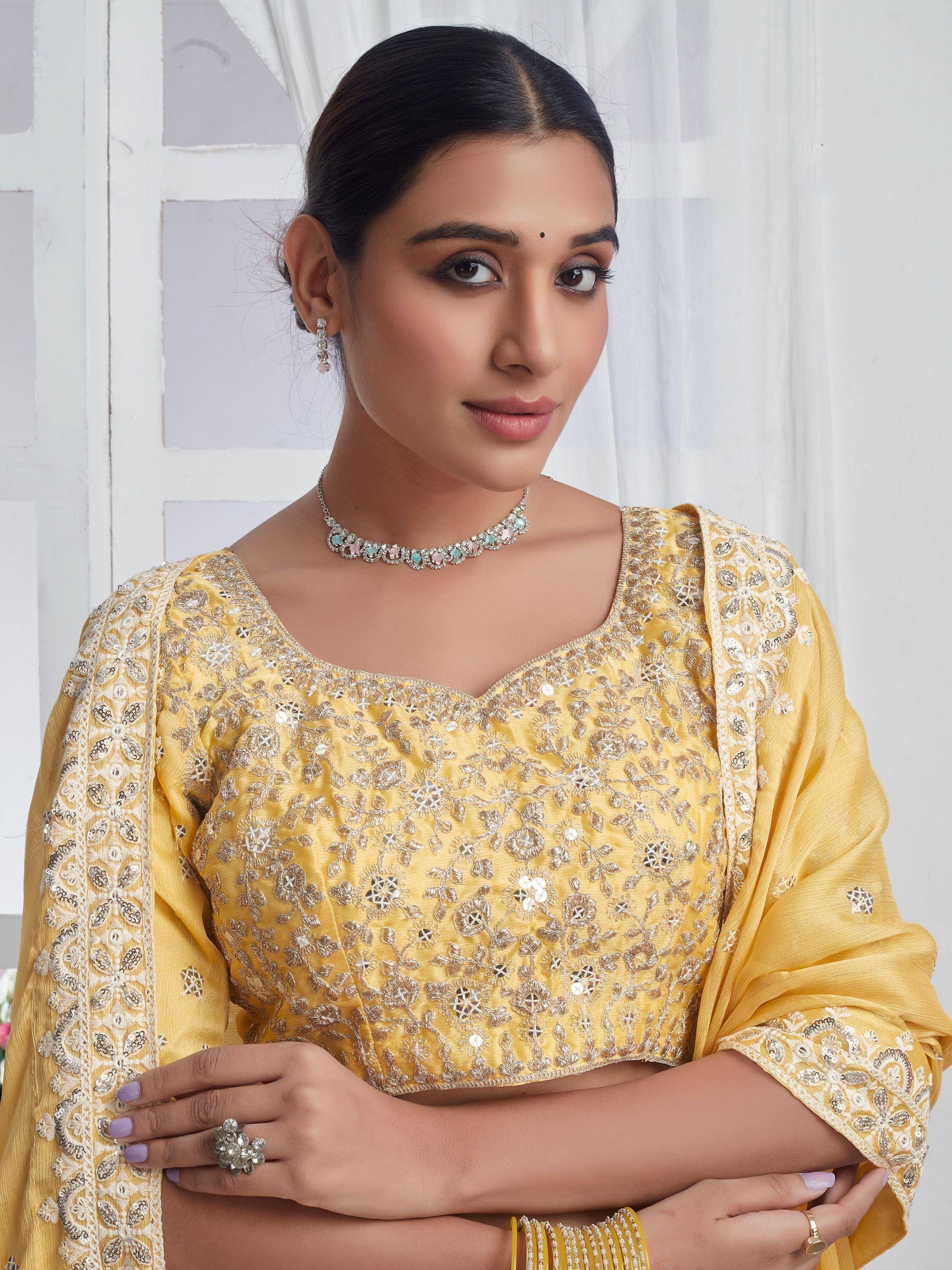 Yellow embroidered ethnic blouse with mirror work, paired with statement jewelry for festive occasions