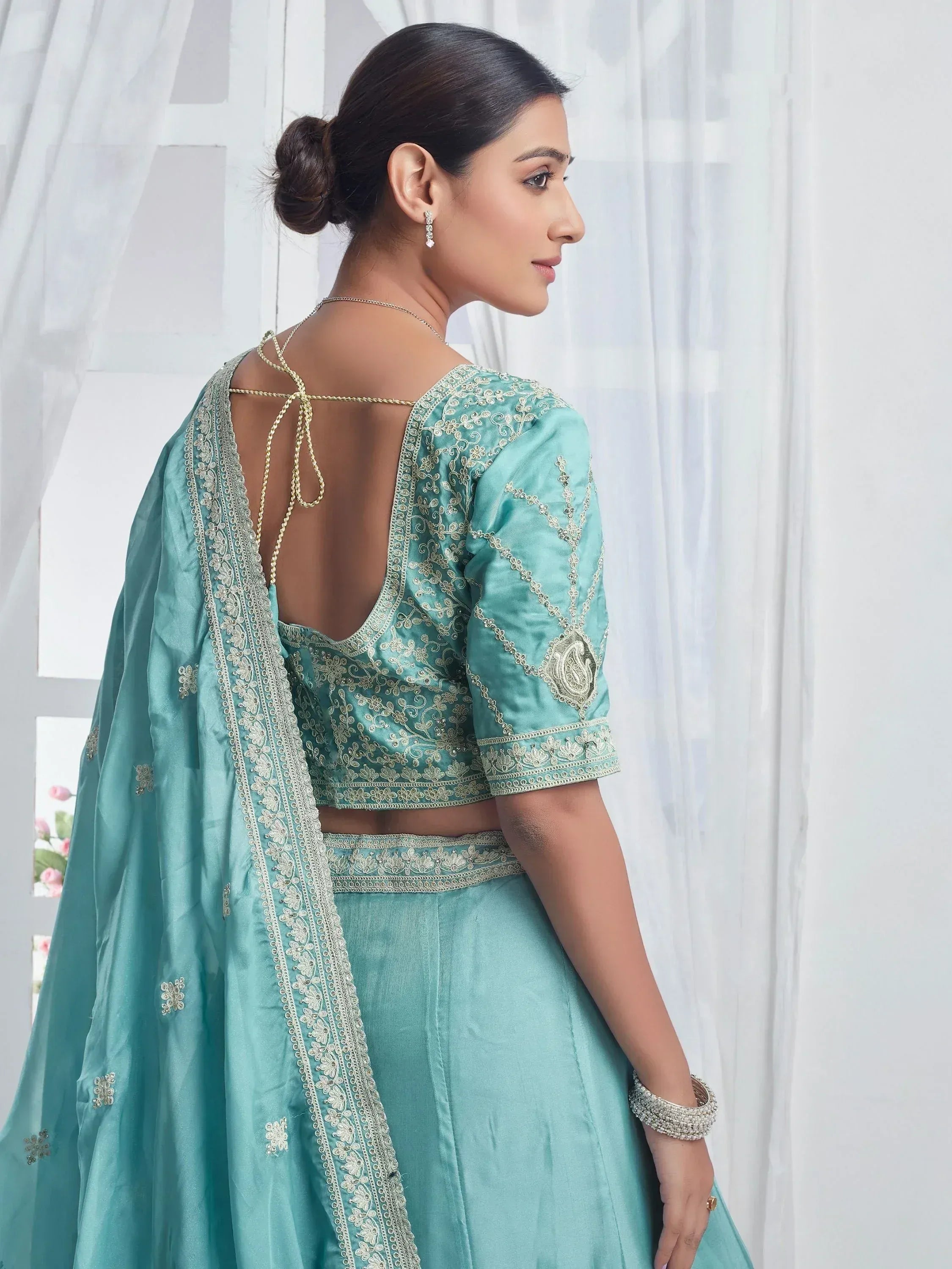 Teal designer lehenga choli with gold embroidery and open back, perfect for Indian ethnic wear occasions
