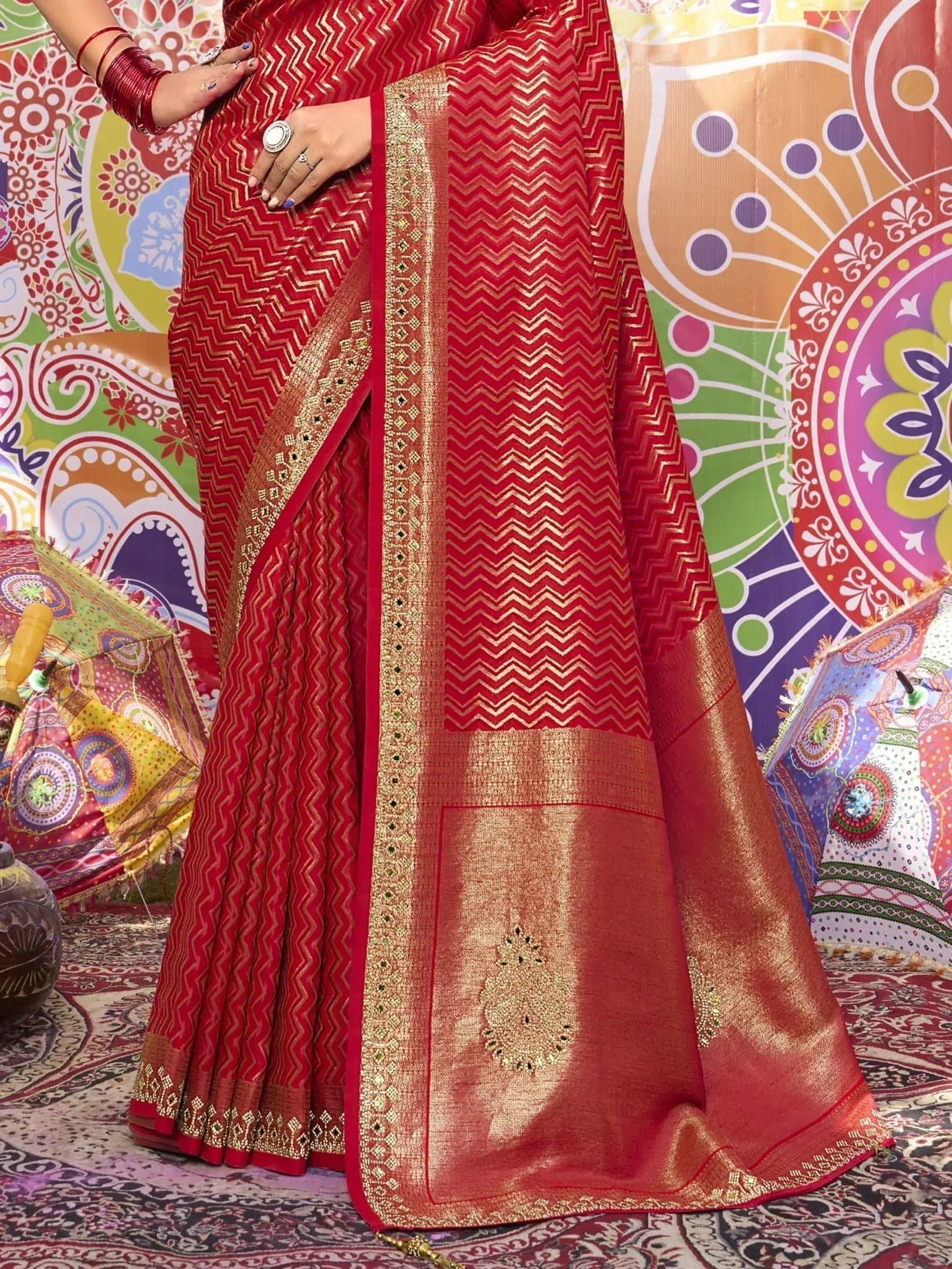 Red and gold zigzag patterned saree with intricate border, styled for ethnic occasions