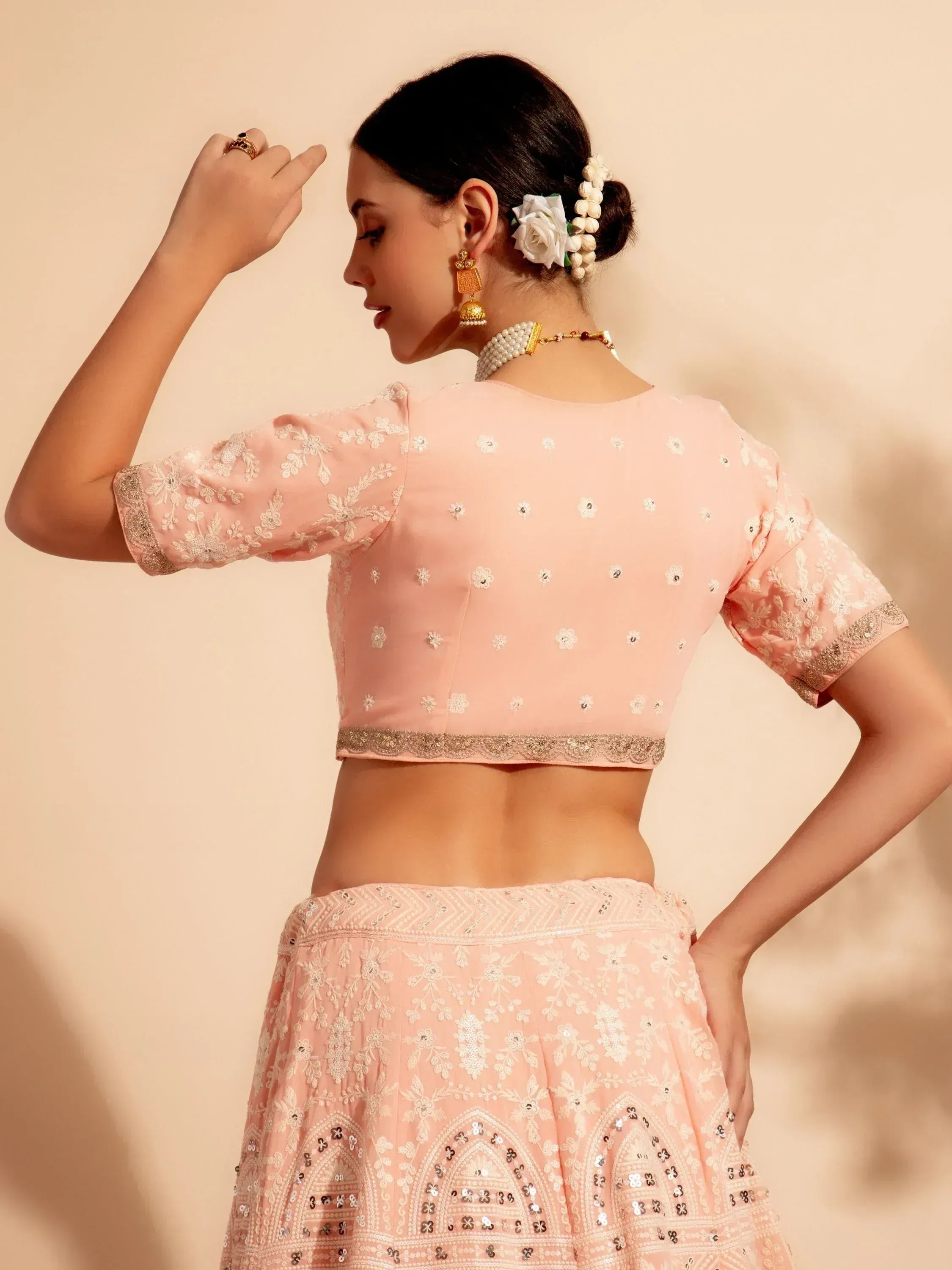 Pink embroidered lehenga choli with floral motifs and gold trim, perfect for Indian ethnic wear occasions.