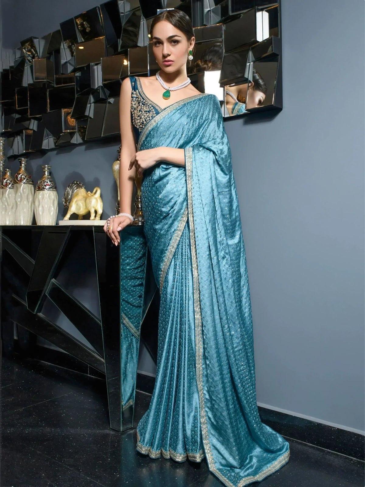 Teal blue designer saree with gold embroidery and embellished border, paired with matching blouse for ethnic wear