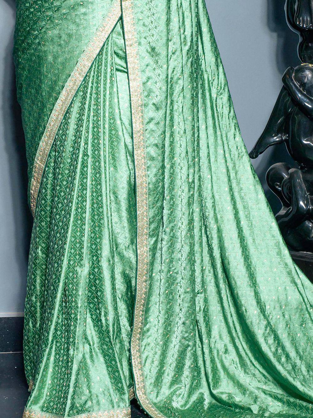 Emerald green designer saree with gold border and intricate patterns, perfect for ethnic occasions.