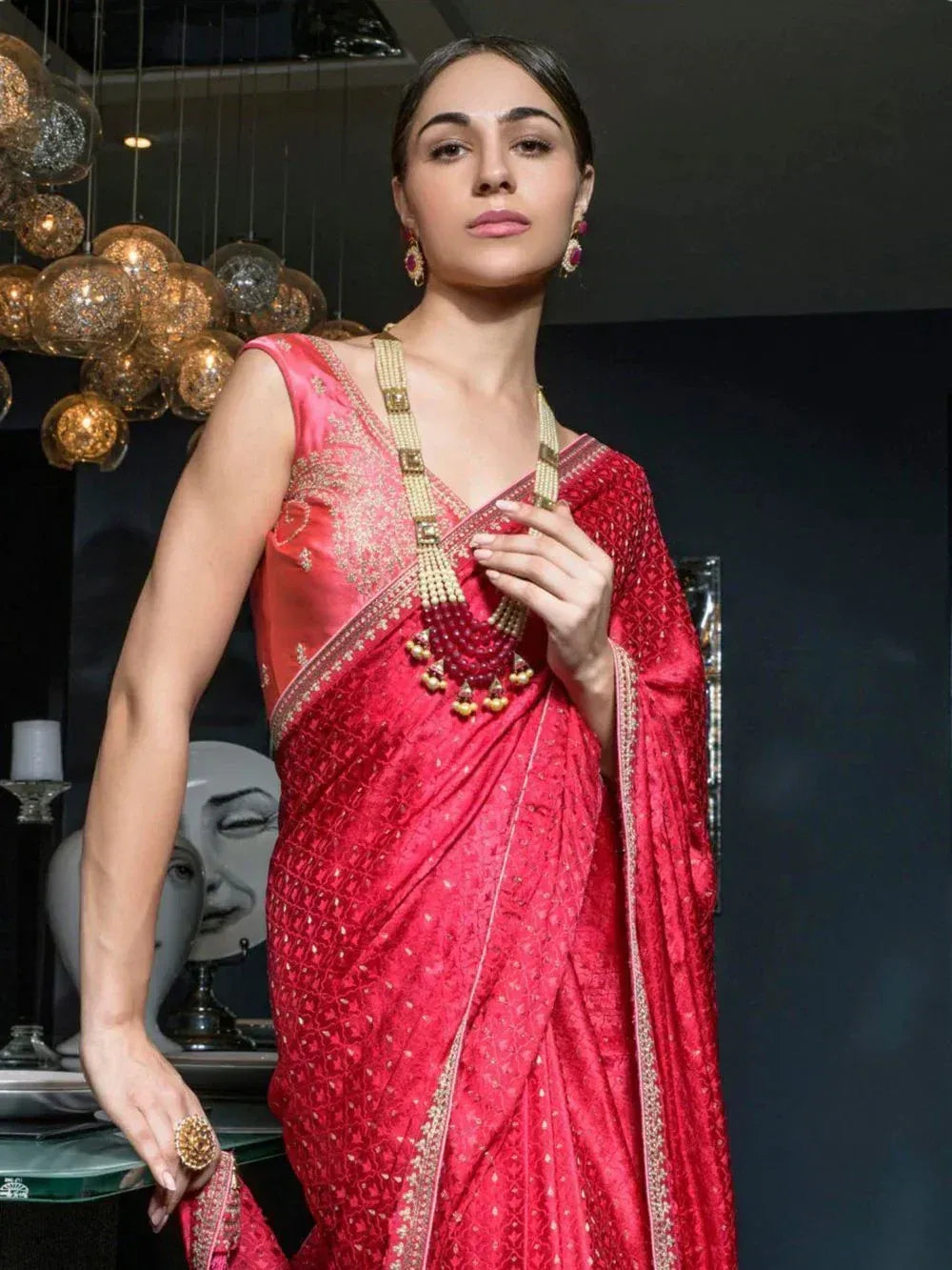 Red embroidered saree with gold detailing, paired with traditional jewelry for Indian ethnic wear