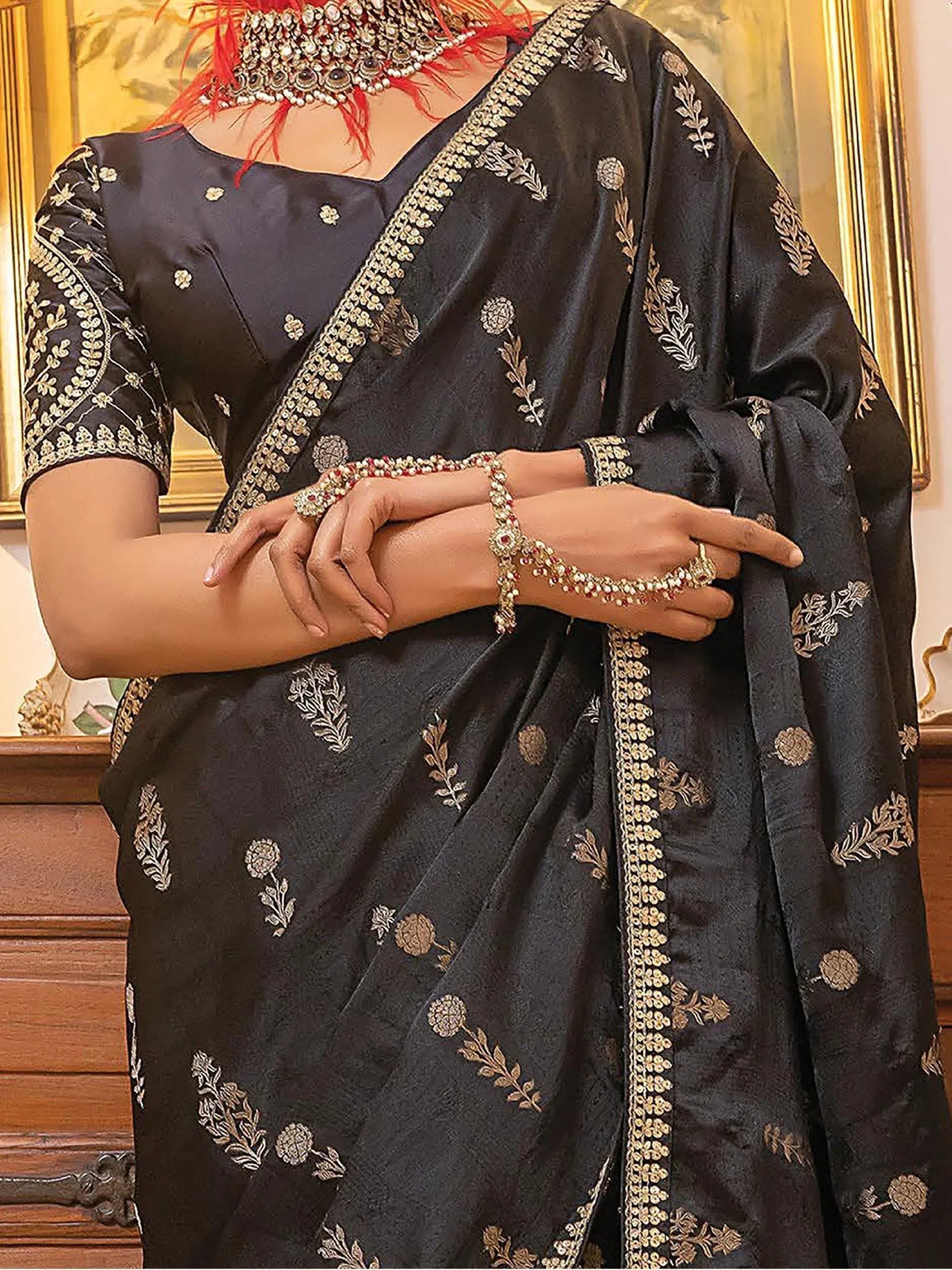 Black embroidered saree with gold floral motifs and matching blouse, styled with traditional jewelry