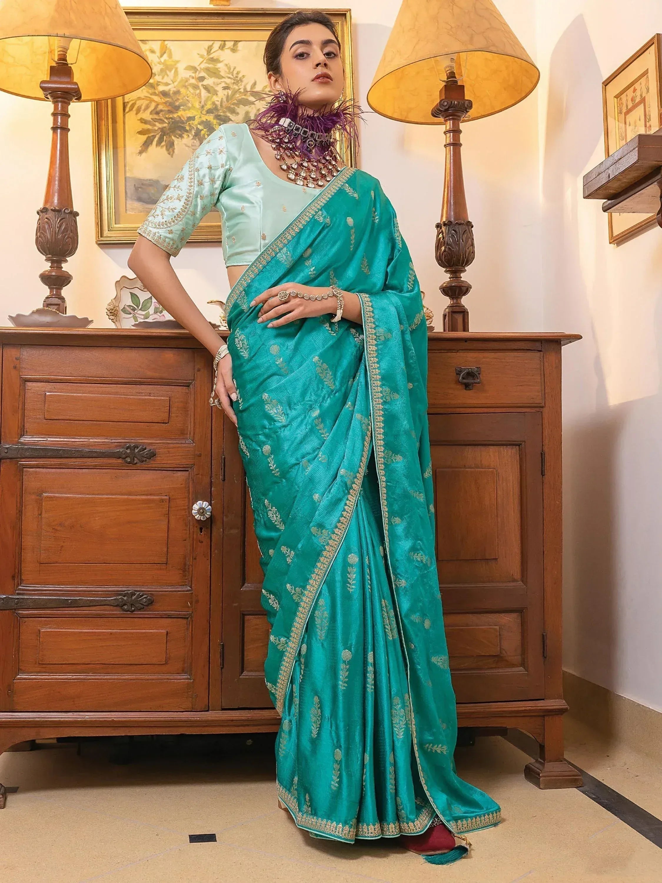 Teal designer saree with gold embroidery, paired with light blue blouse, perfect for Indian ethnic occasions.