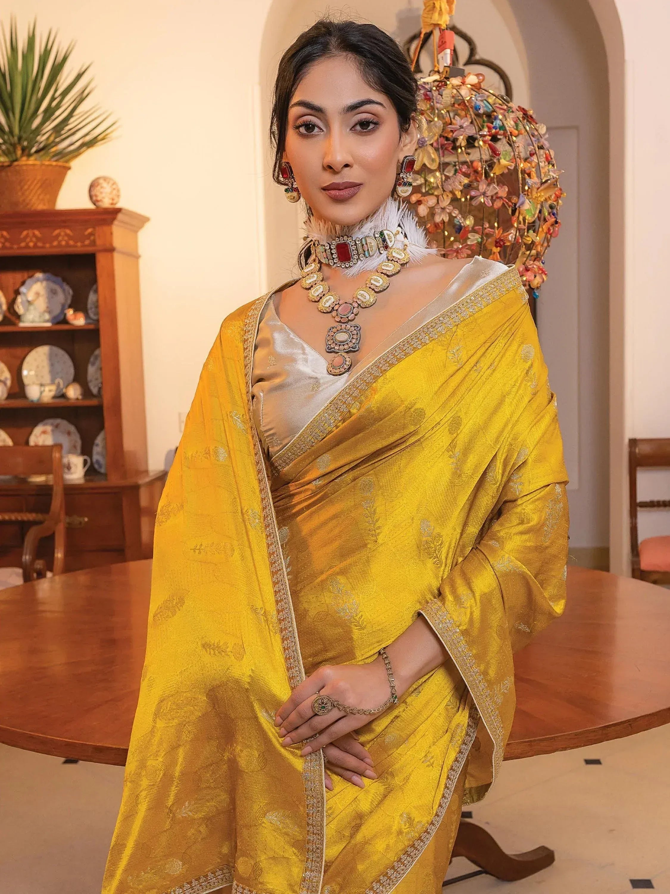 Elegant woman in golden yellow designer saree with intricate embroidery and traditional jewelry