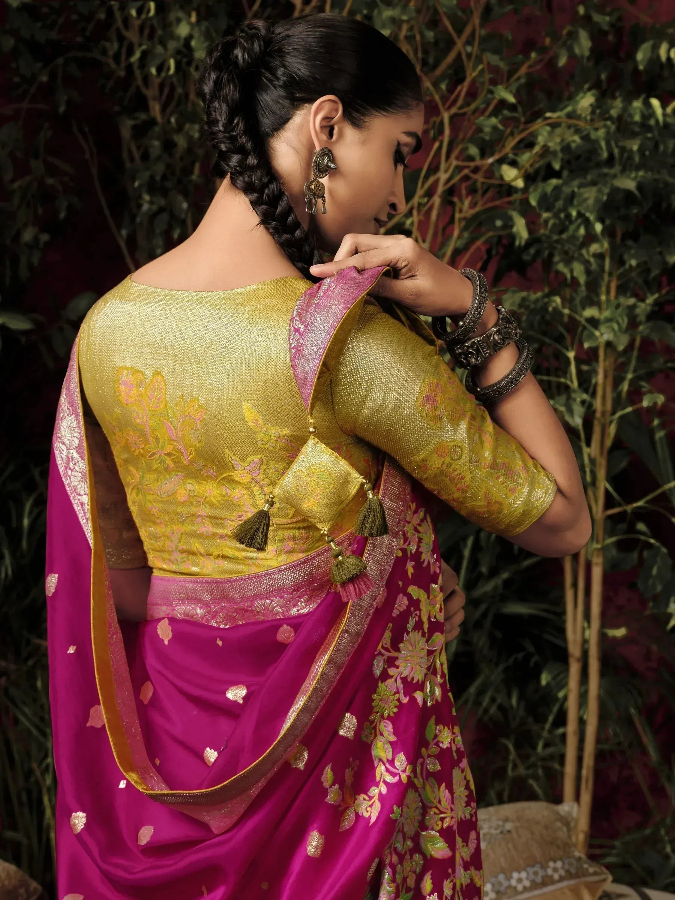 Woman in vibrant pink and gold embroidered saree with floral motifs, traditional Indian ethnic wear