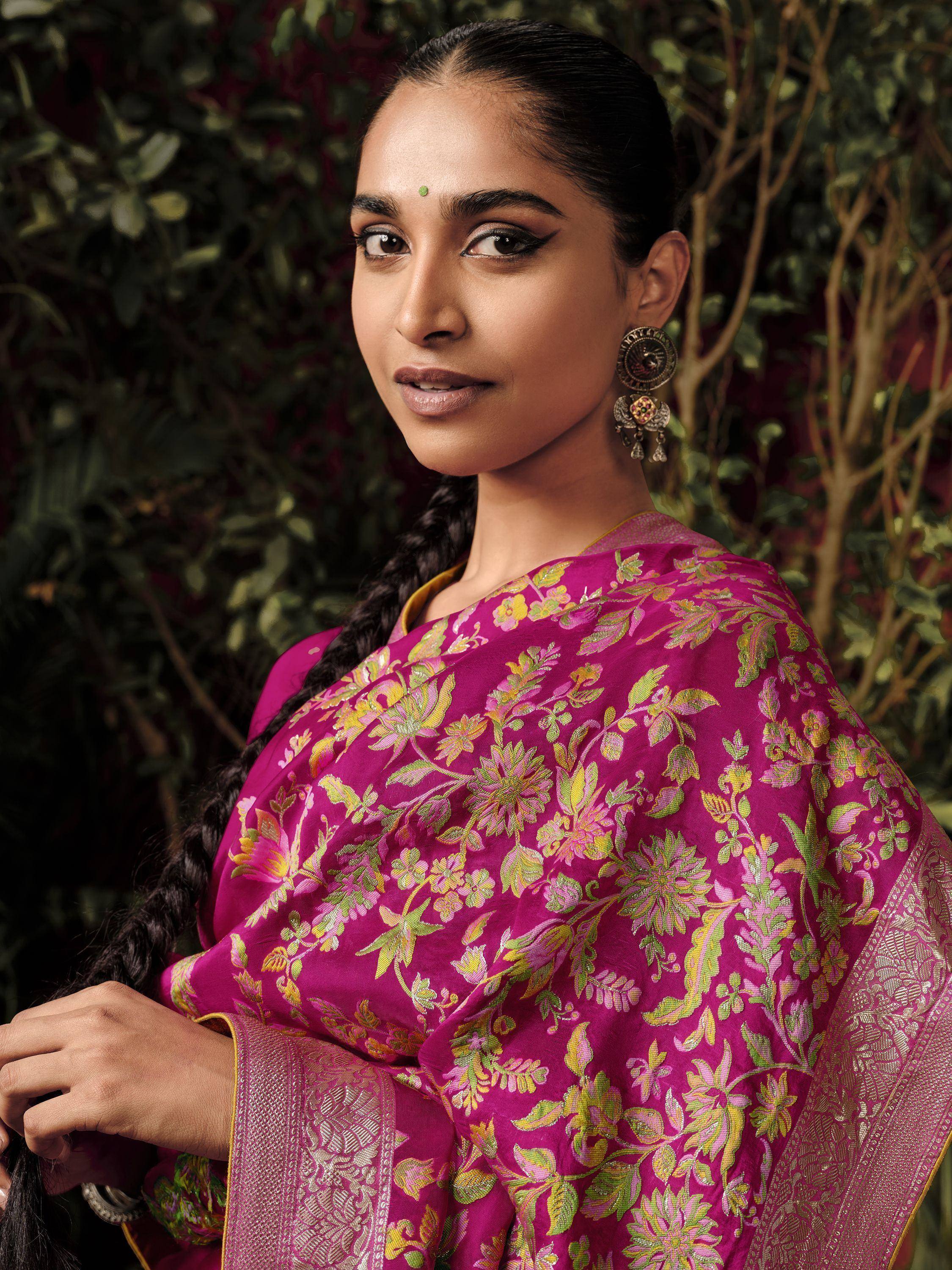 Woman in vibrant magenta floral saree with gold border, traditional Indian ethnic wear