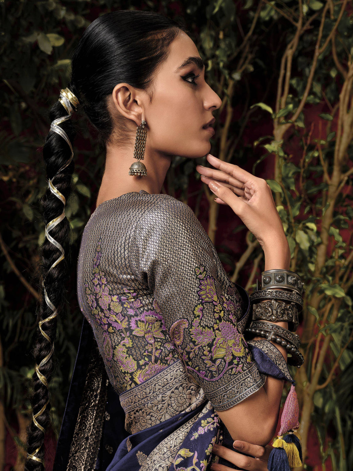 Woman in elegant Indian ethnic saree with gold and purple embroidery, traditional jhumka earrings, and braided hair