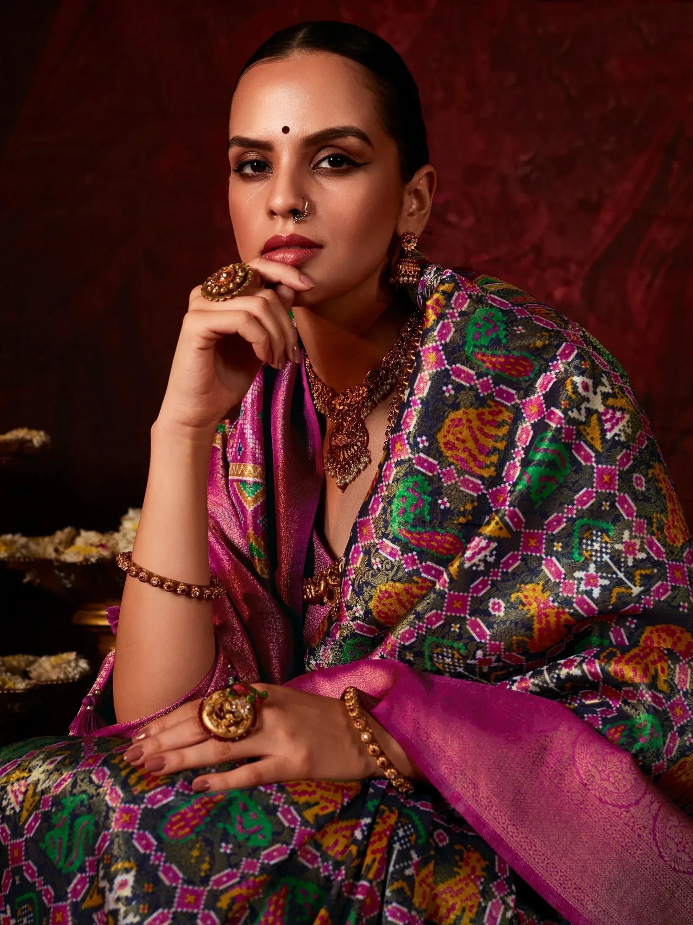 Woman in vibrant ethnic saree with intricate patterns, traditional jewelry, and bold makeup for festive occasions.