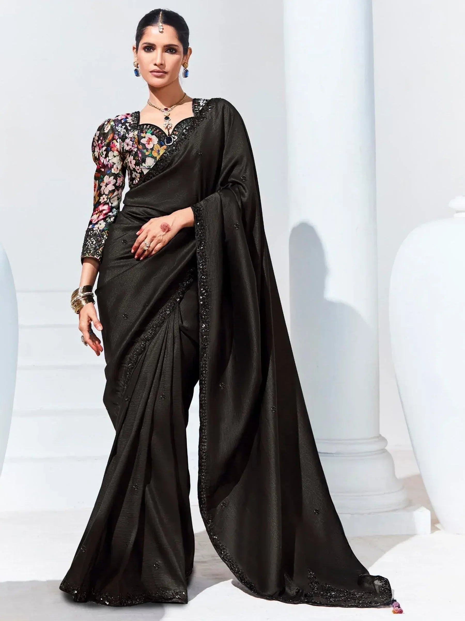 Black saree with floral blouse, sequin border, and ethnic jewelry for Indian women's wear