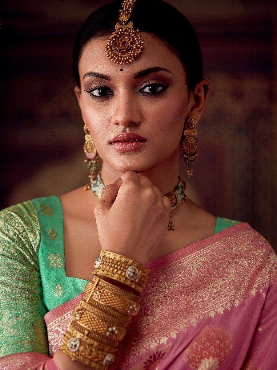 Woman in pink and green designer saree with gold jewelry, traditional Indian ethnic wear