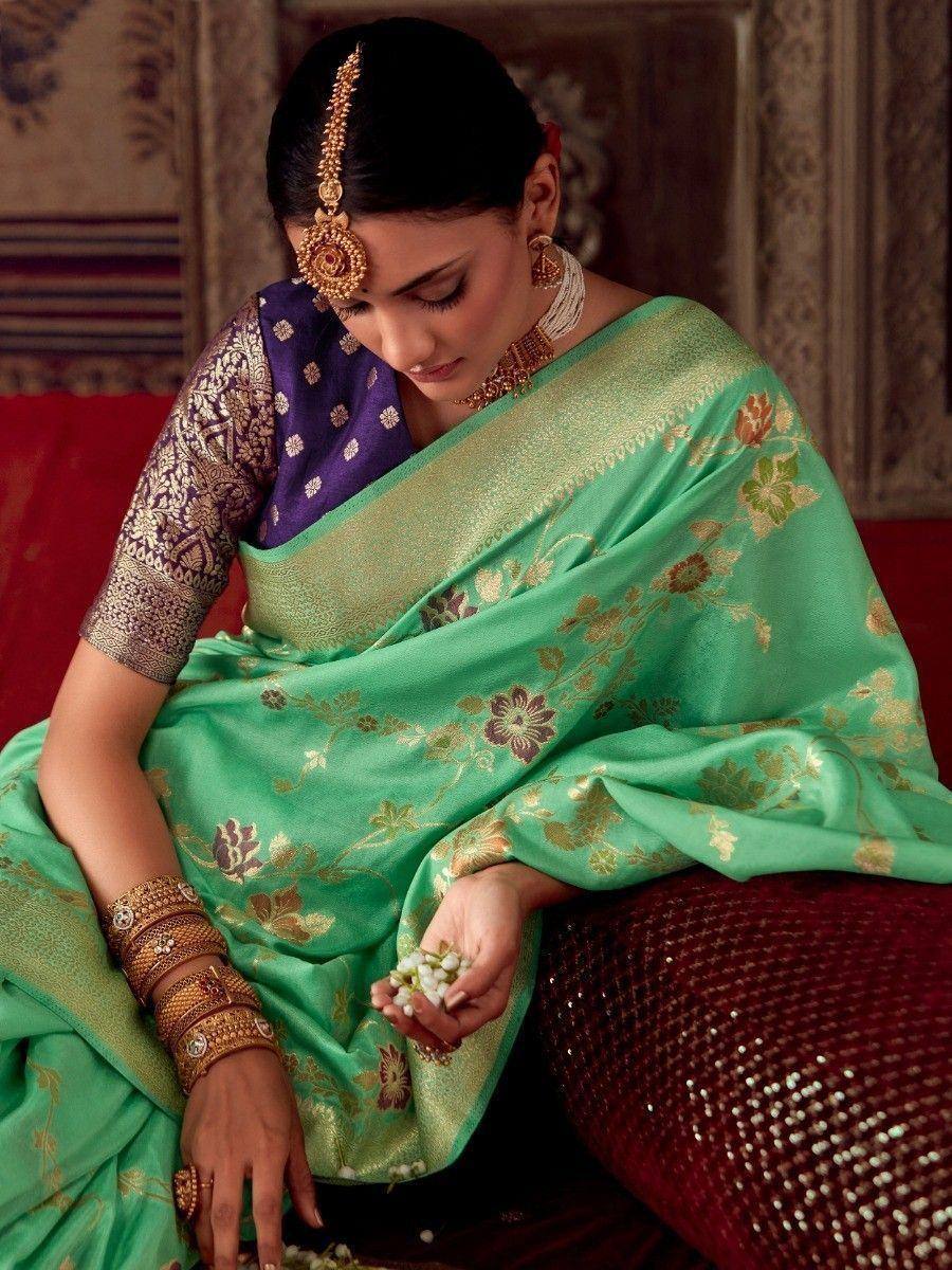 Elegant green floral saree with gold embroidery, paired with purple blouse and traditional jewelry