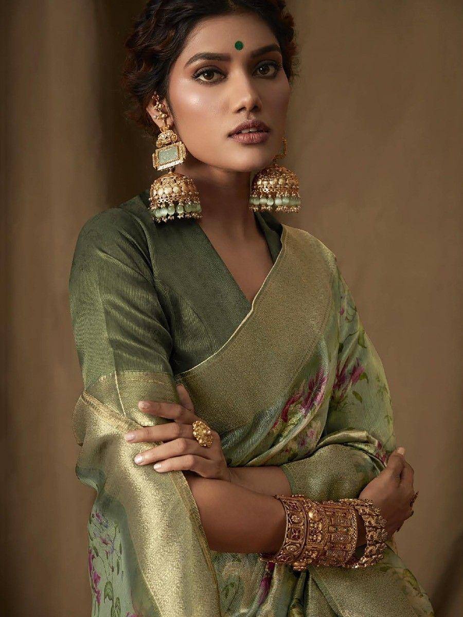 Elegant green floral saree with gold border, paired with traditional jhumka earrings and temple jewelry for Indian ethnic wear.