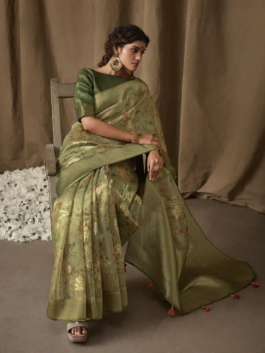 Elegant olive green floral saree with gold embroidery, paired with matching blouse and tassels, styled for ethnic occasions.